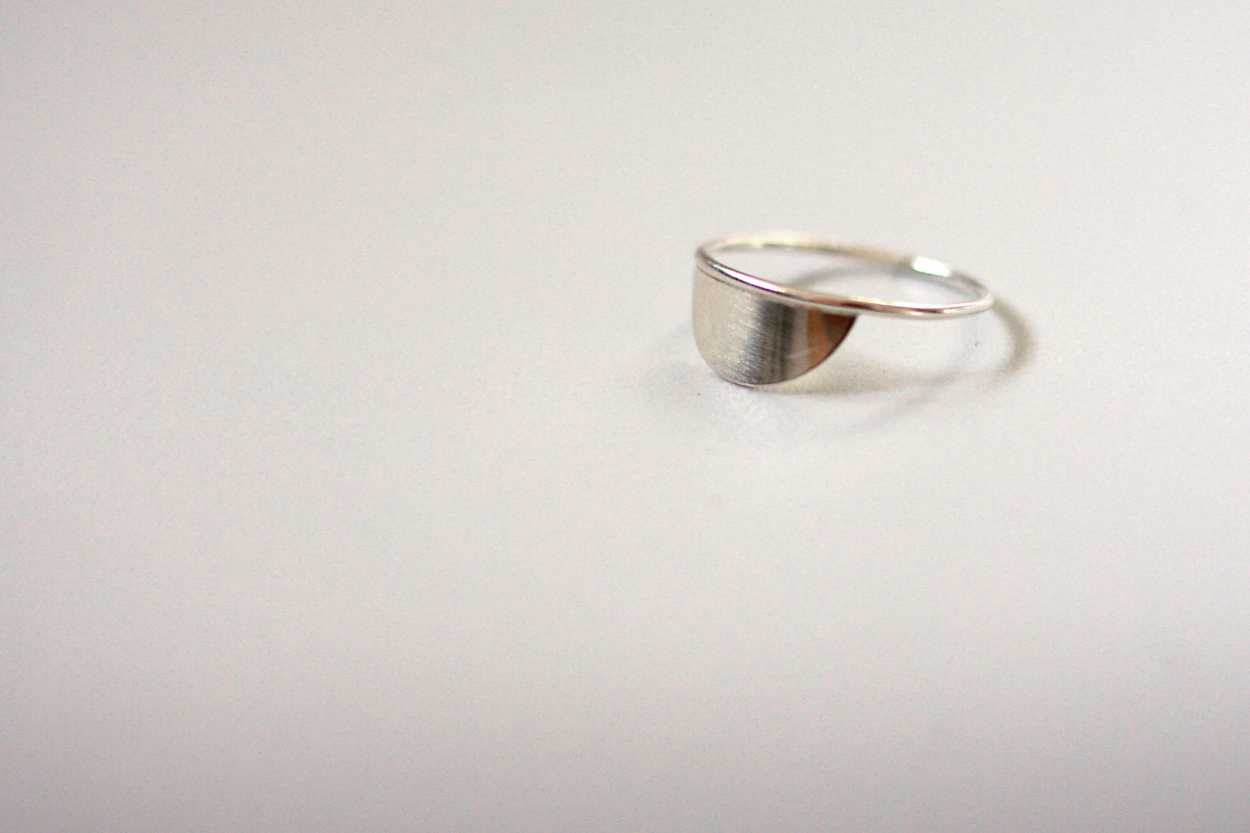 A silver half circle ring on a while background