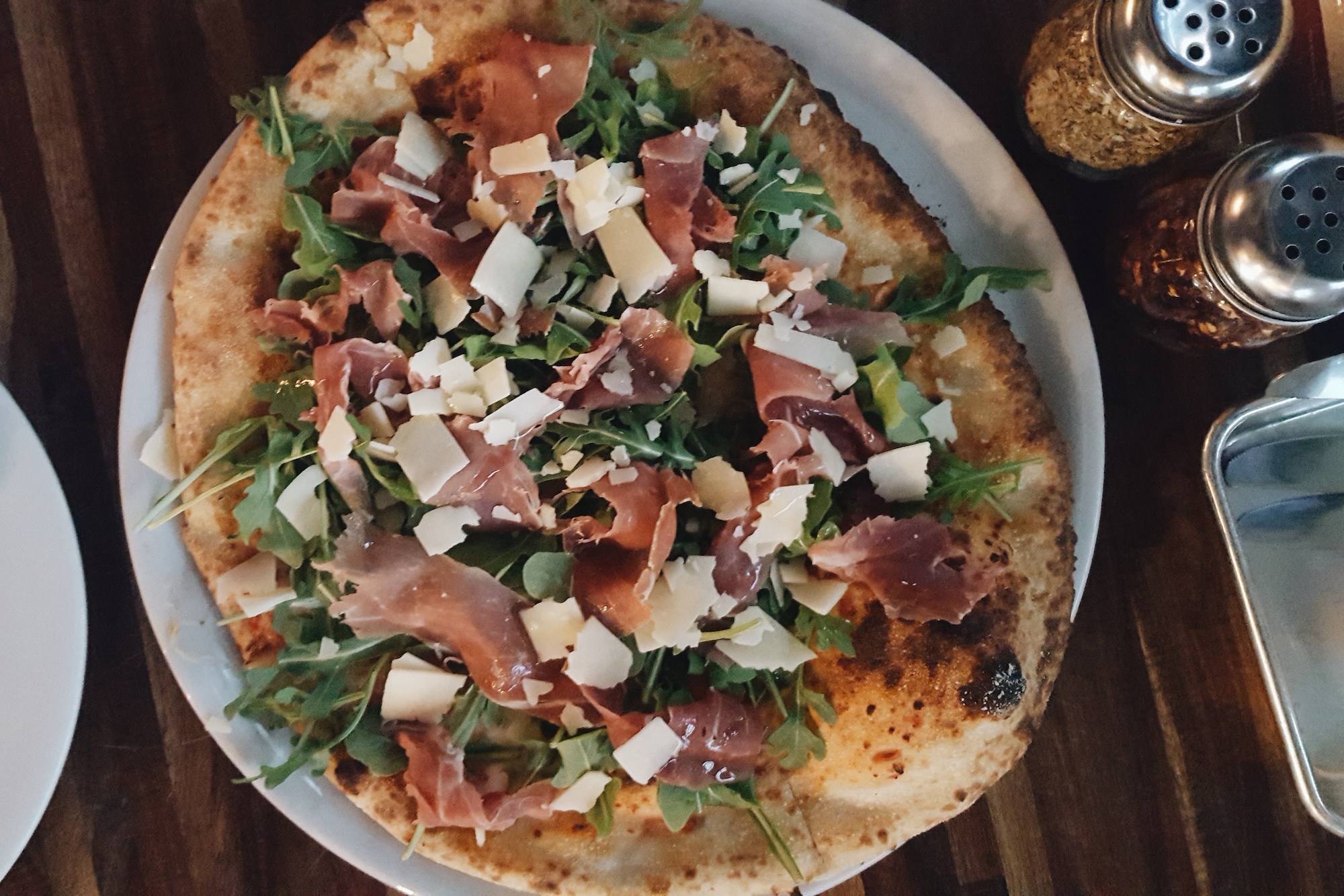 A pizza with arugula and prosciutto 