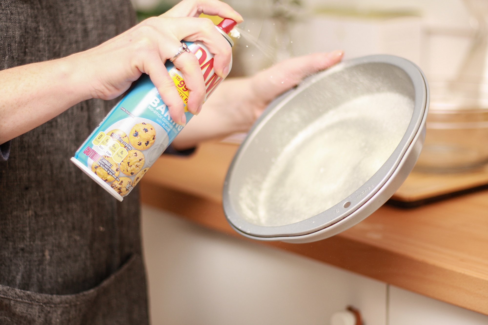 Alyssa sprays nonstick spray into a cake tin