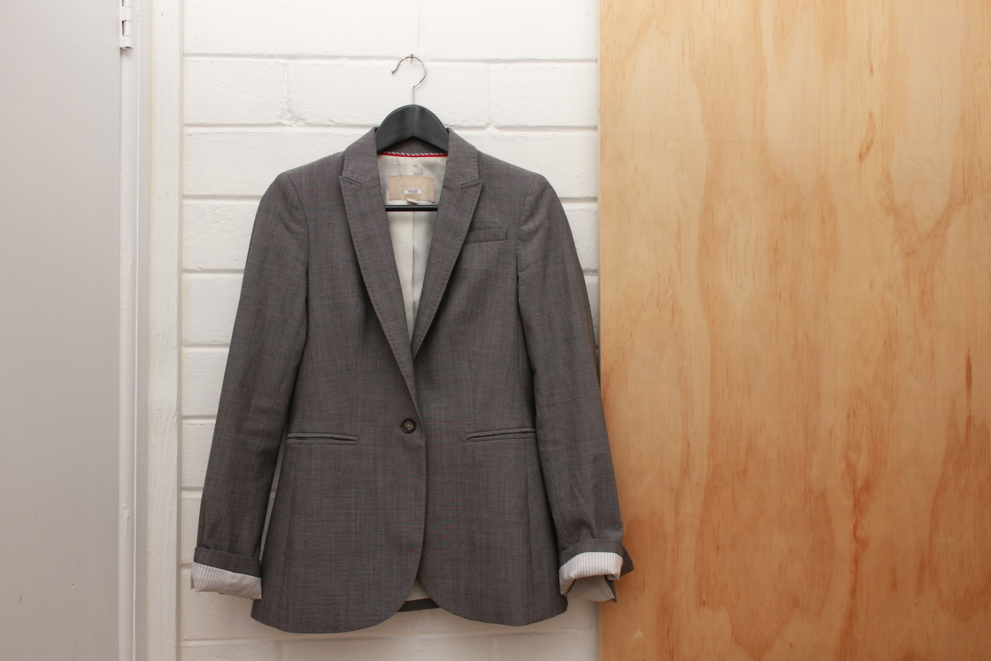 A grey blazer from Banana Republic hangs on a hanger
