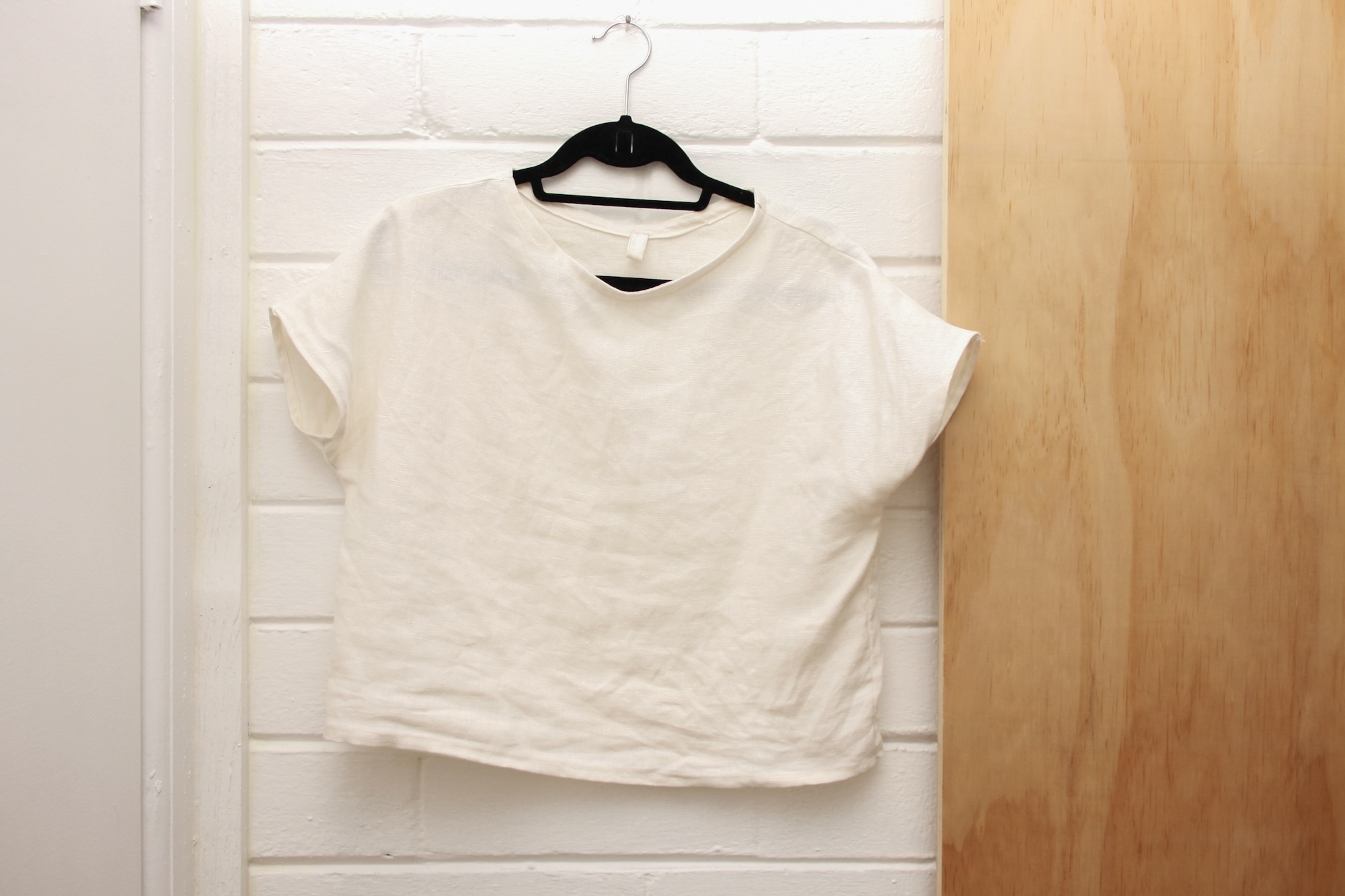 a handmade linen tee hangs on a hook