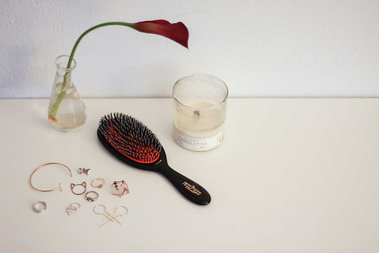 A hairbrush and candle with jewelry purchased while traveling