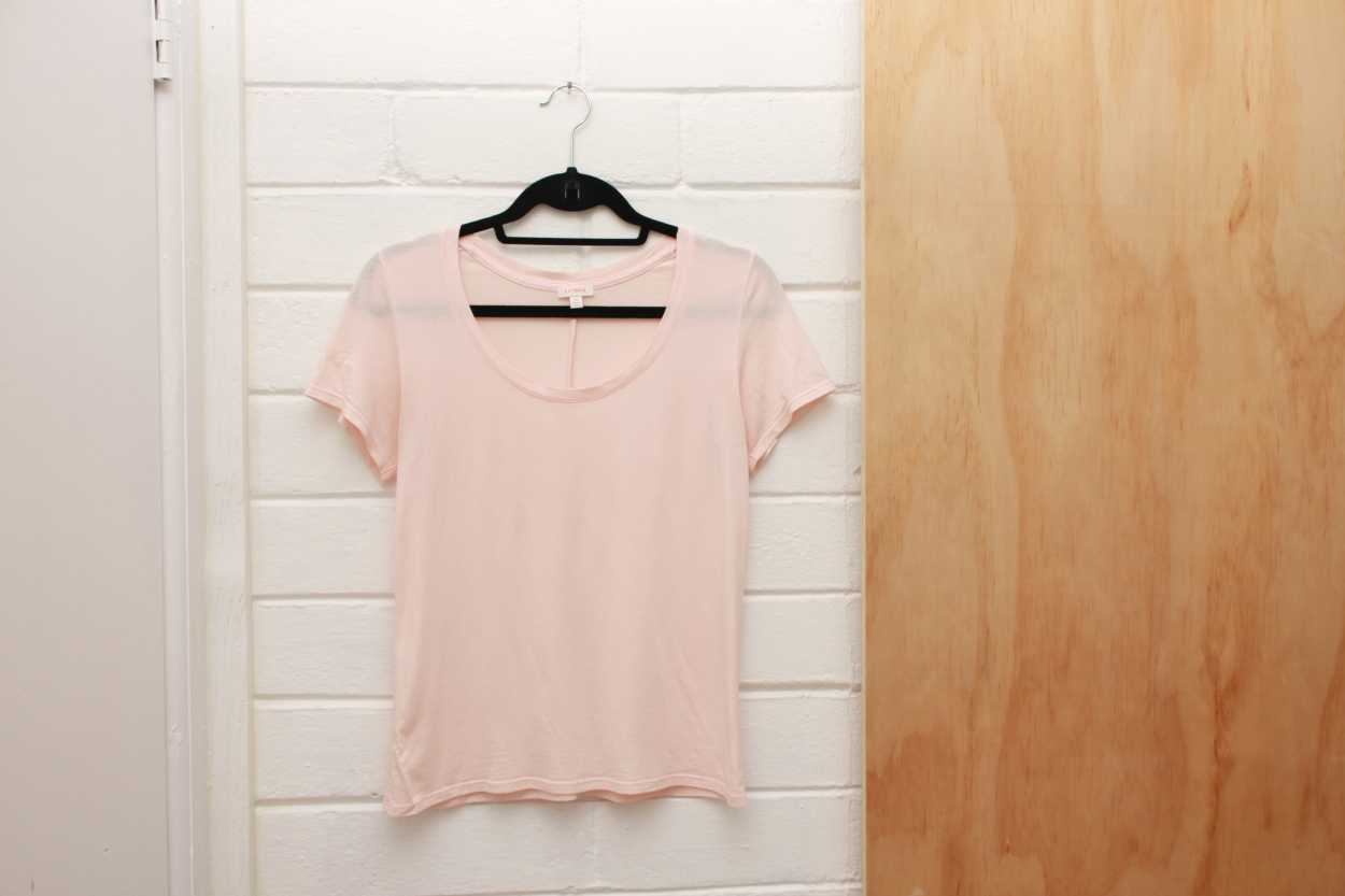 A pink Pima Tee from Cuyana hangs on a hanger