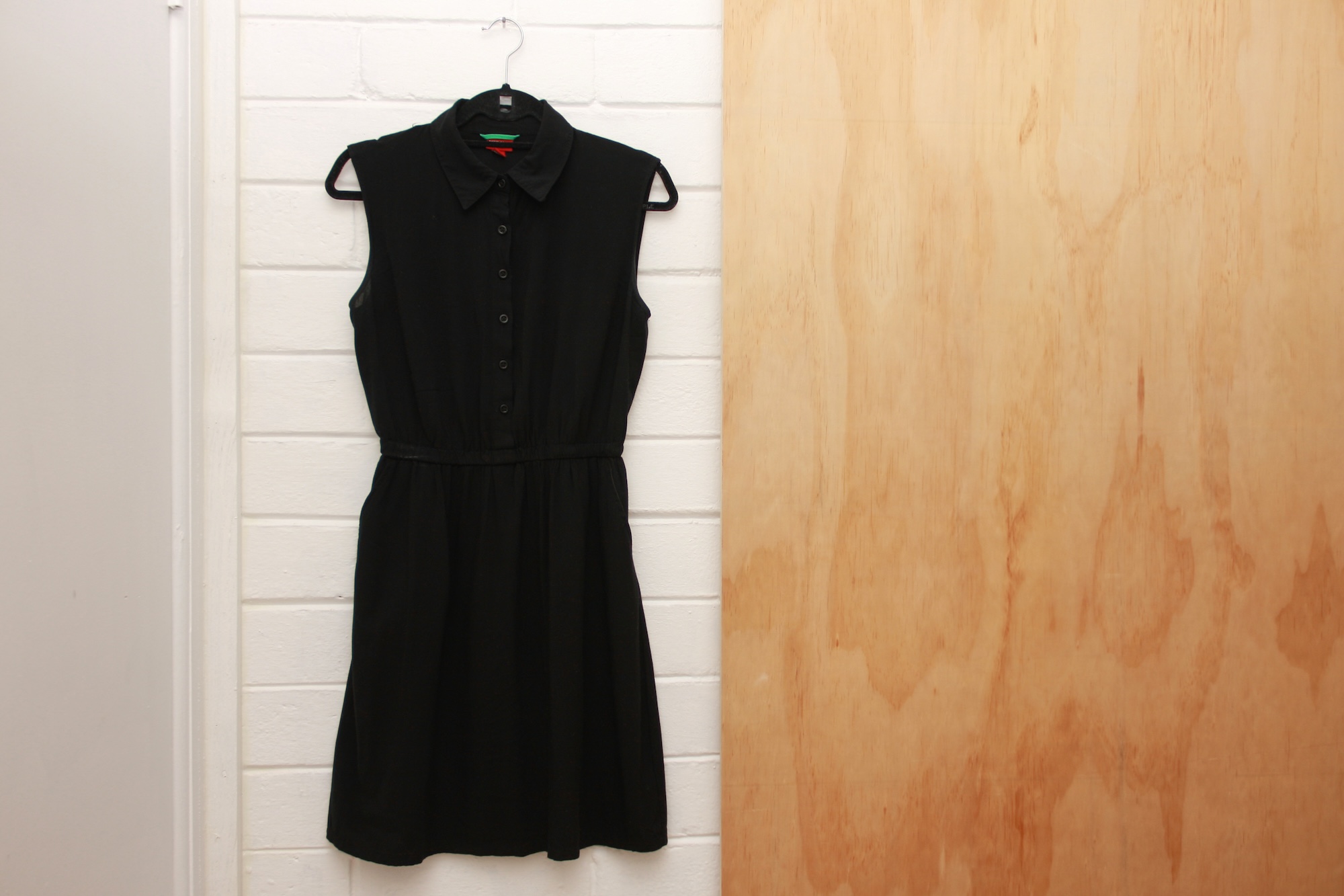 a black shirtdress hangs on a hanger