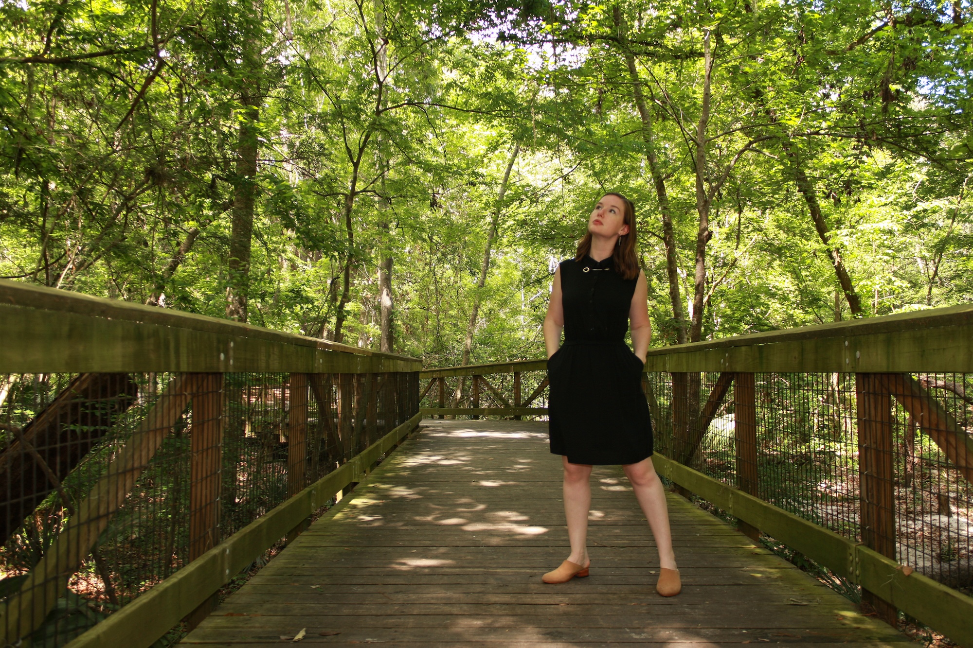 Alyssa wears a black shirtdress with nude mules and looks upward