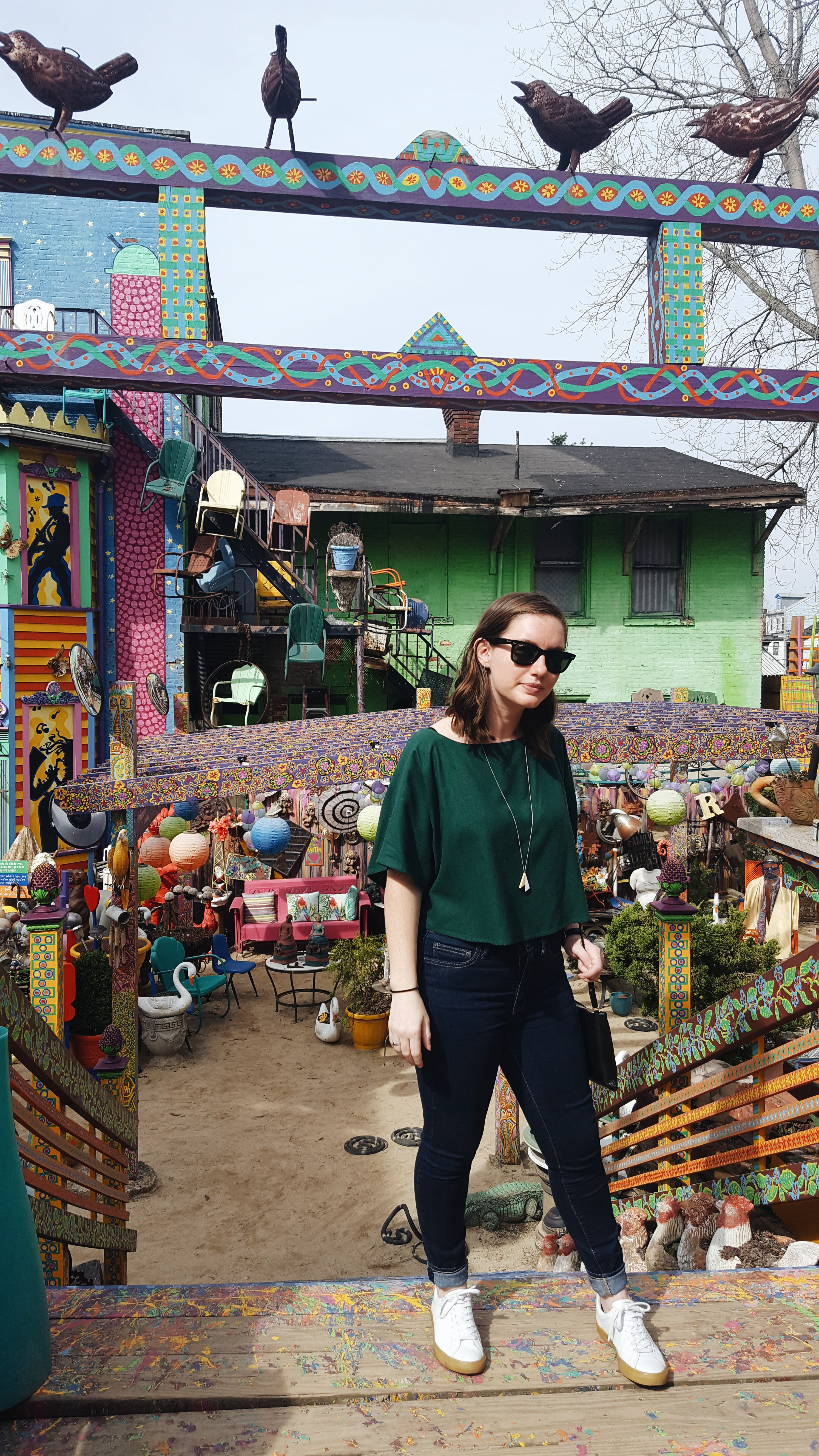 Alyssa stands on the stairs at Randyland in a green top and blue jeans