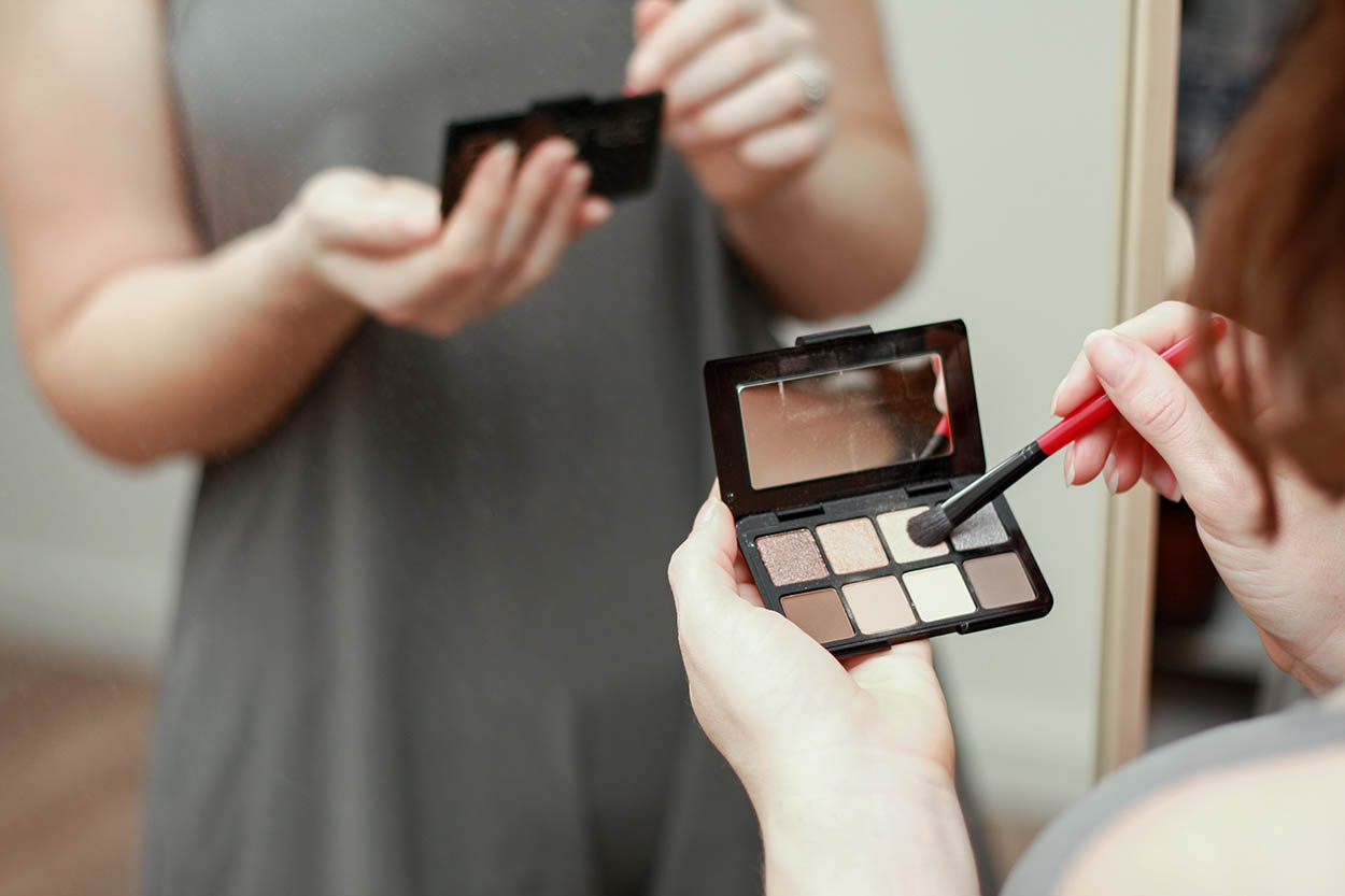 Alyssa dips a brush in a travel eyeshadow palette