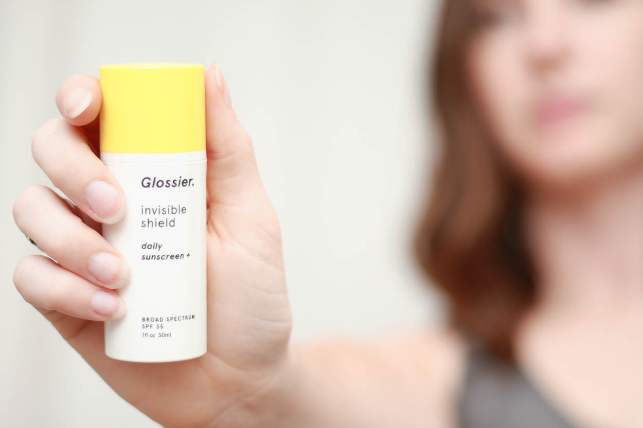 Alyssa holds a bottle of sunscreen from Glossier