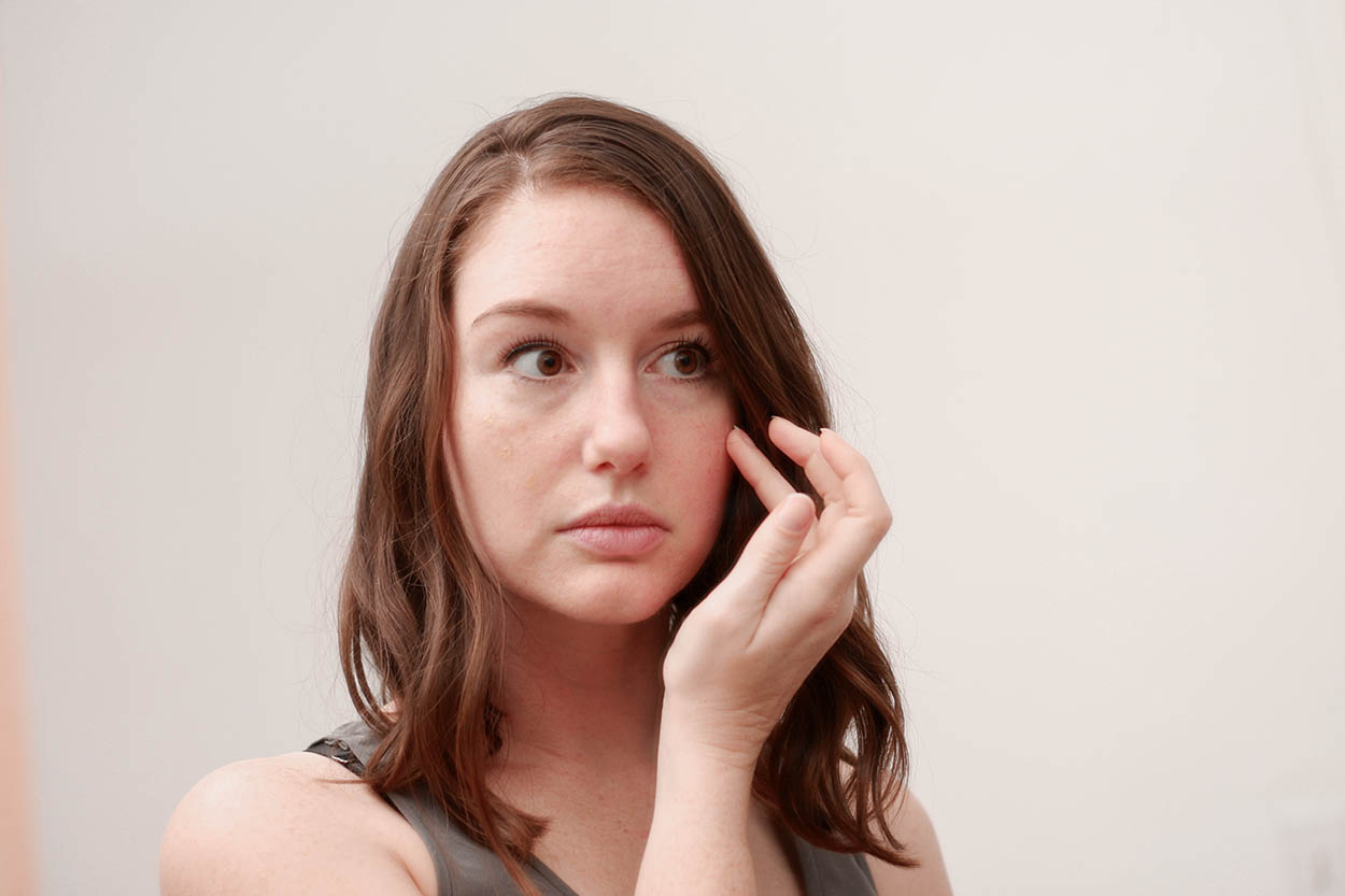 Alyssa applies foundation to her cheek