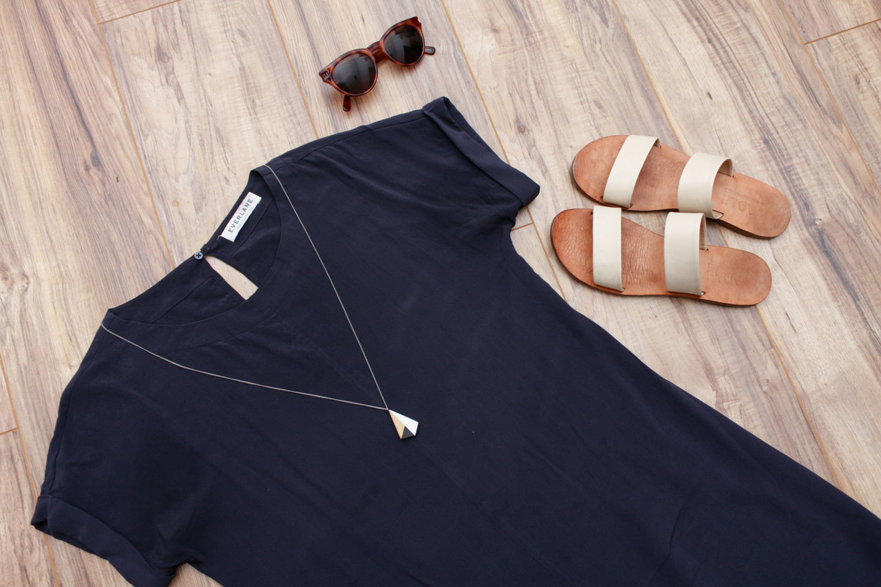 A navy silk dress, white sandals, and brown sunglasses