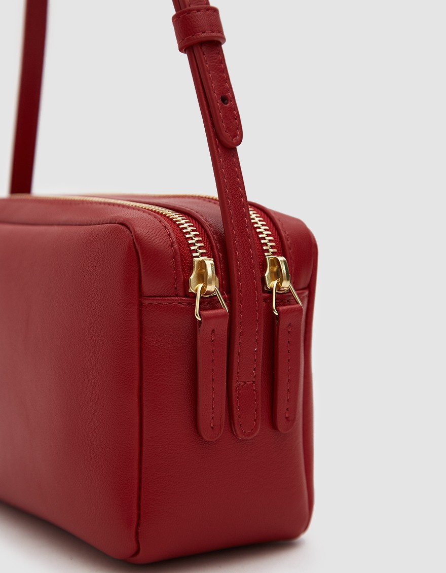 A red purse with two gold zippered pockets