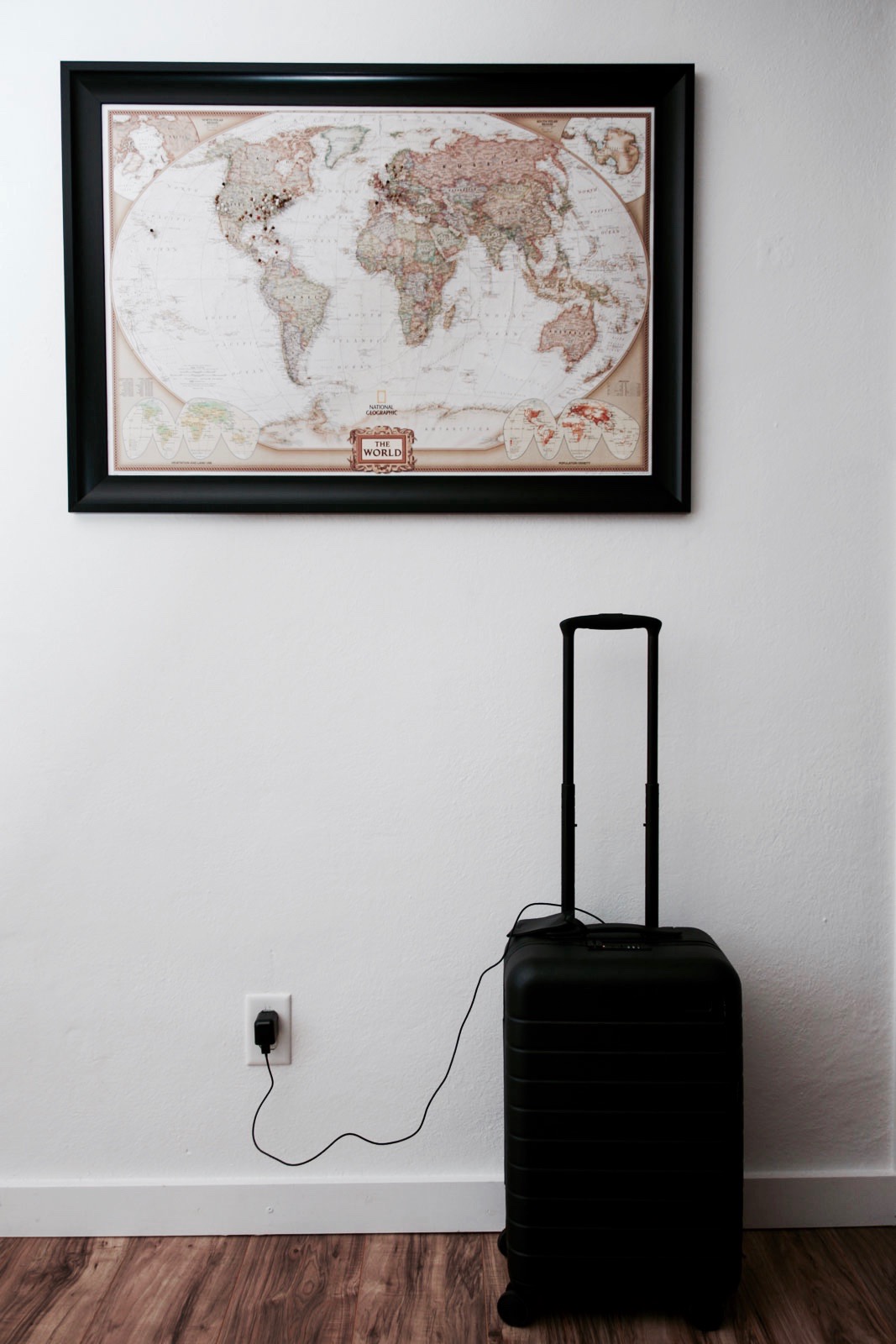 The Away carry-on suitcase charges using an outlet placed by a pin map