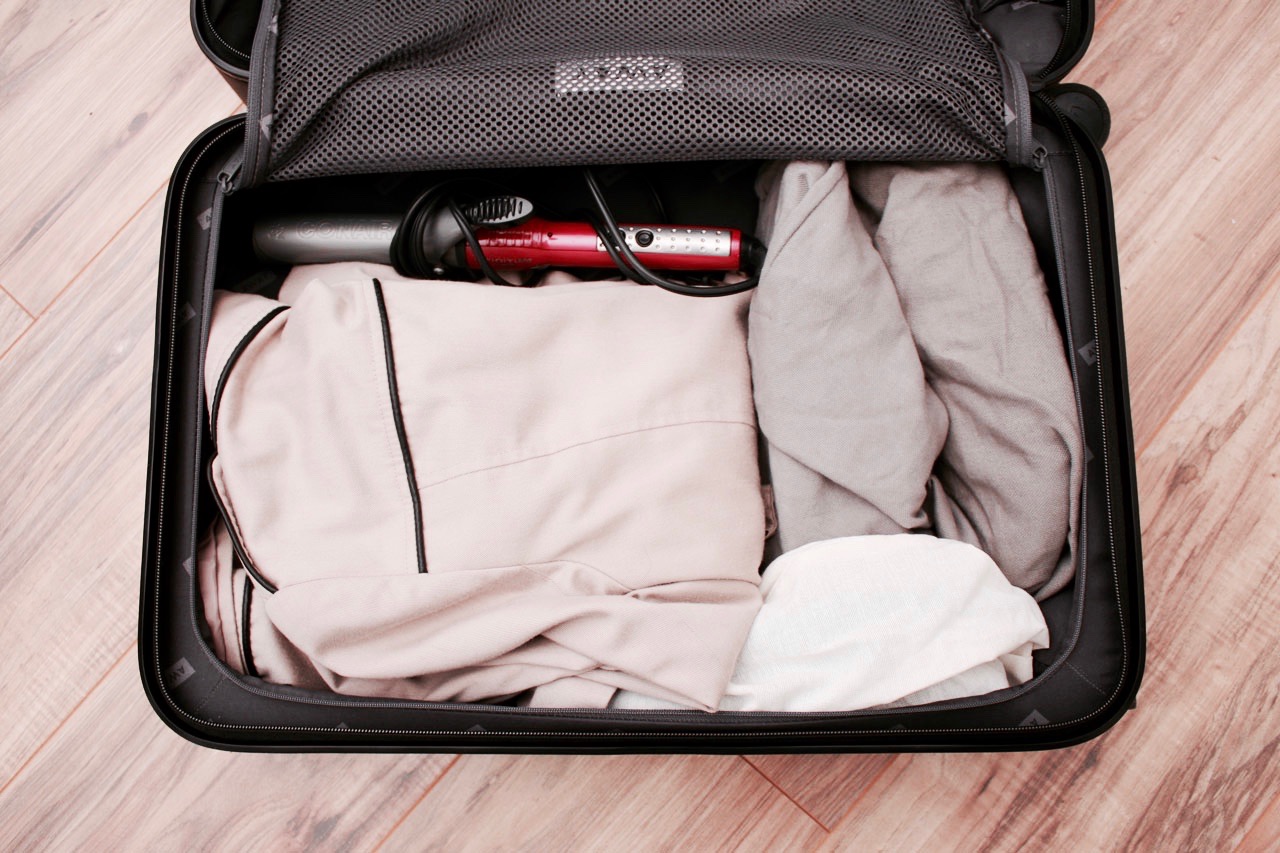 The zipper side of the Carry-On is packed with a curling iron, trench coat and shoes