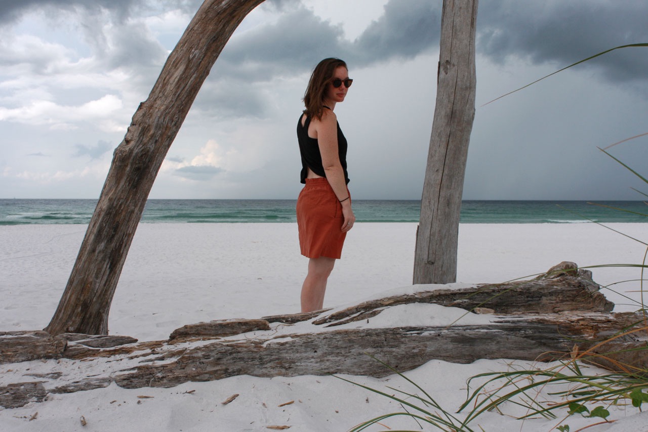 Alyssa stands on the beach in a frame made of driftwood