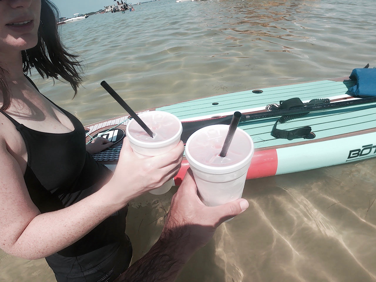 Alyssa and Michael "cheers" with daiquiris on their paddleboards