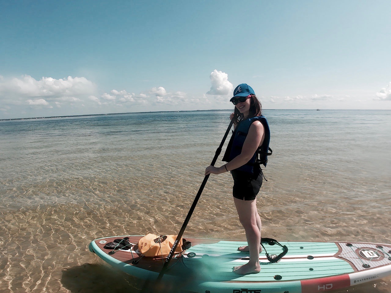 Alyssa stands on a SUP board and paddles in the gulf