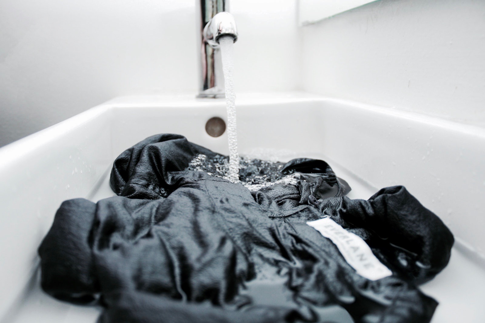 A silk dress from Everlane is rinsed in a sink
