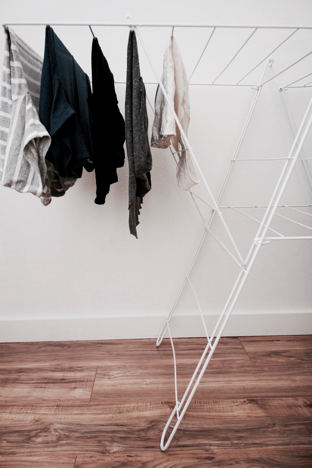 Several garments hang to dry on a drying rack