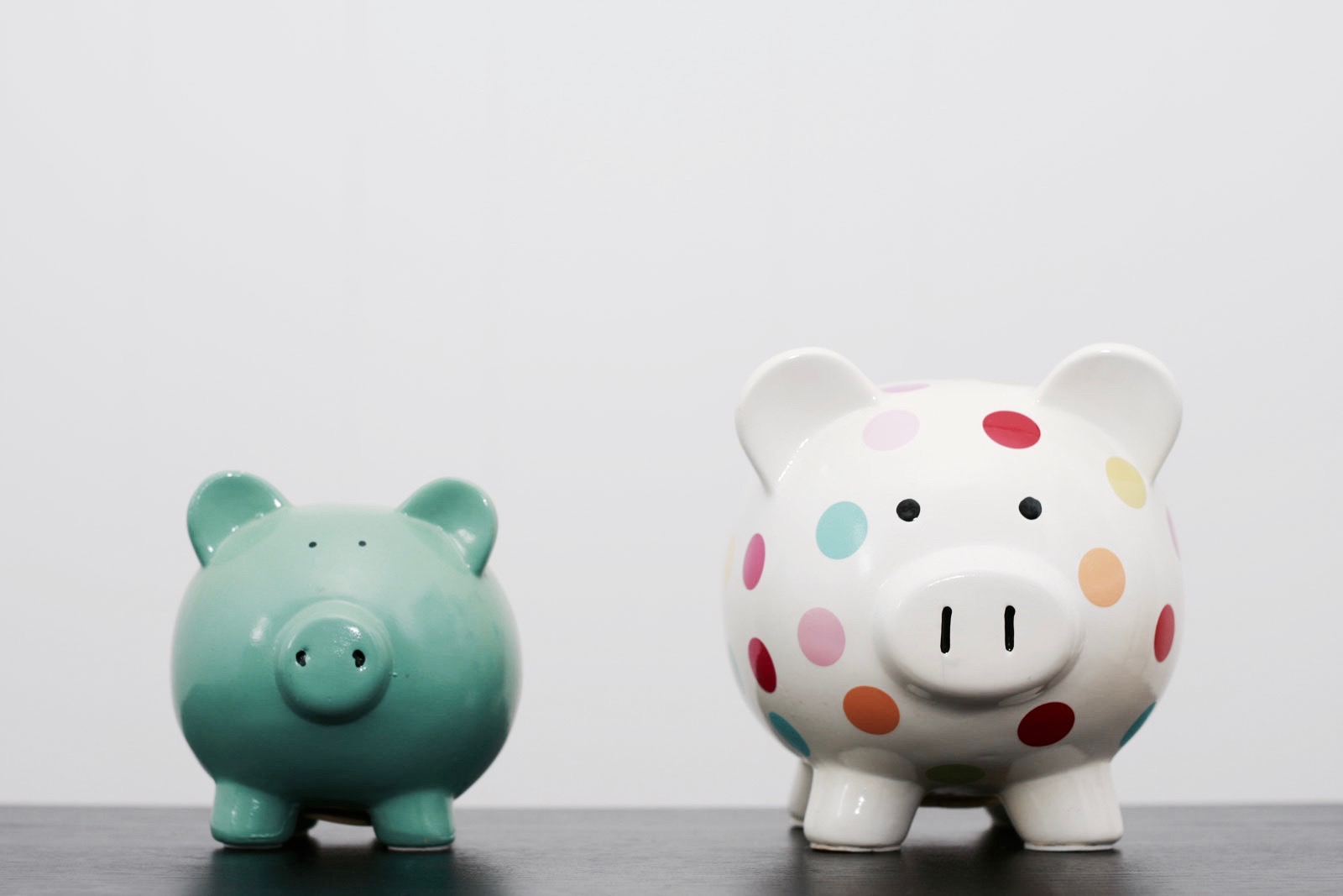 two piggy banks: A polka dot one and a green one