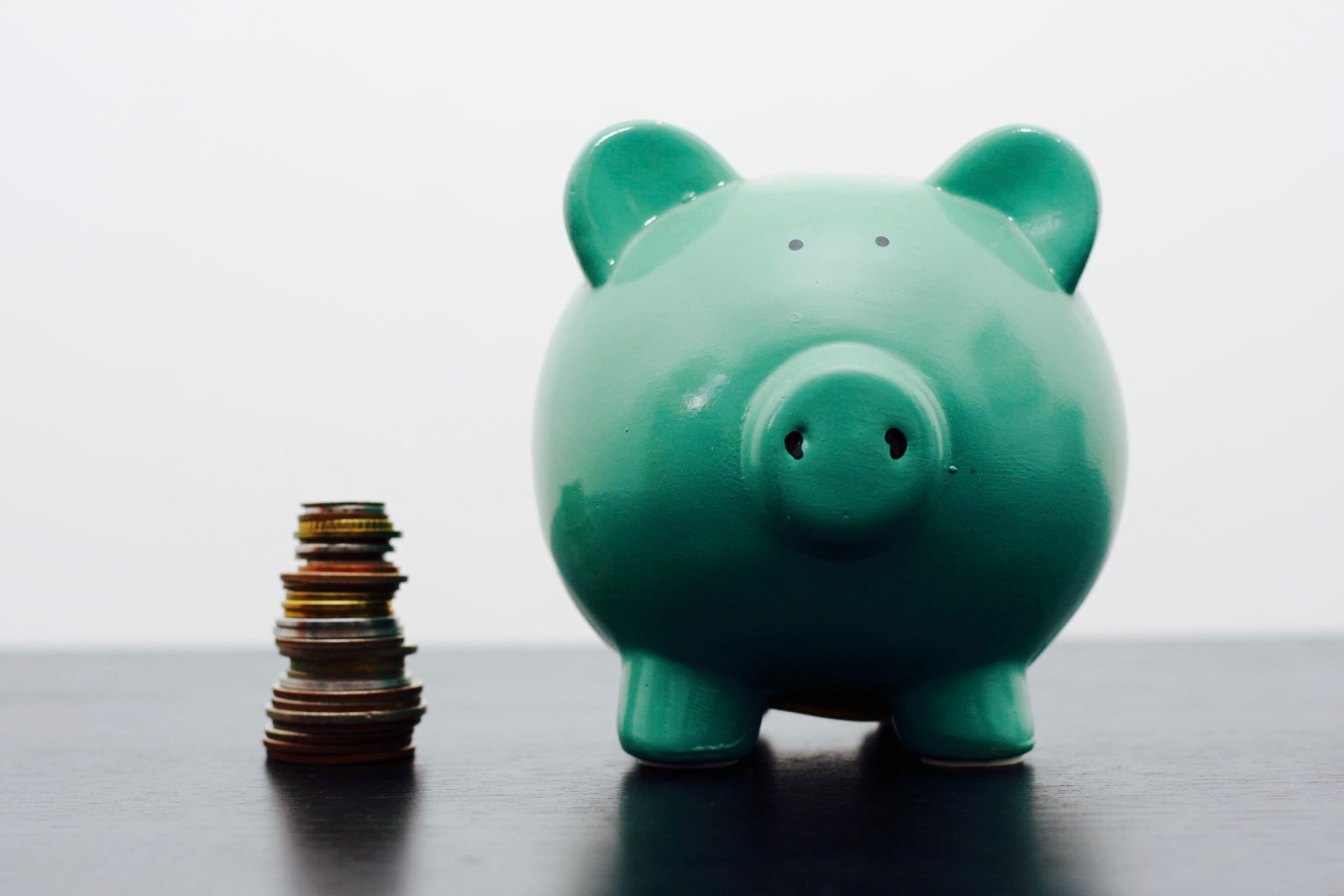 A green piggy bank with a stack of coins