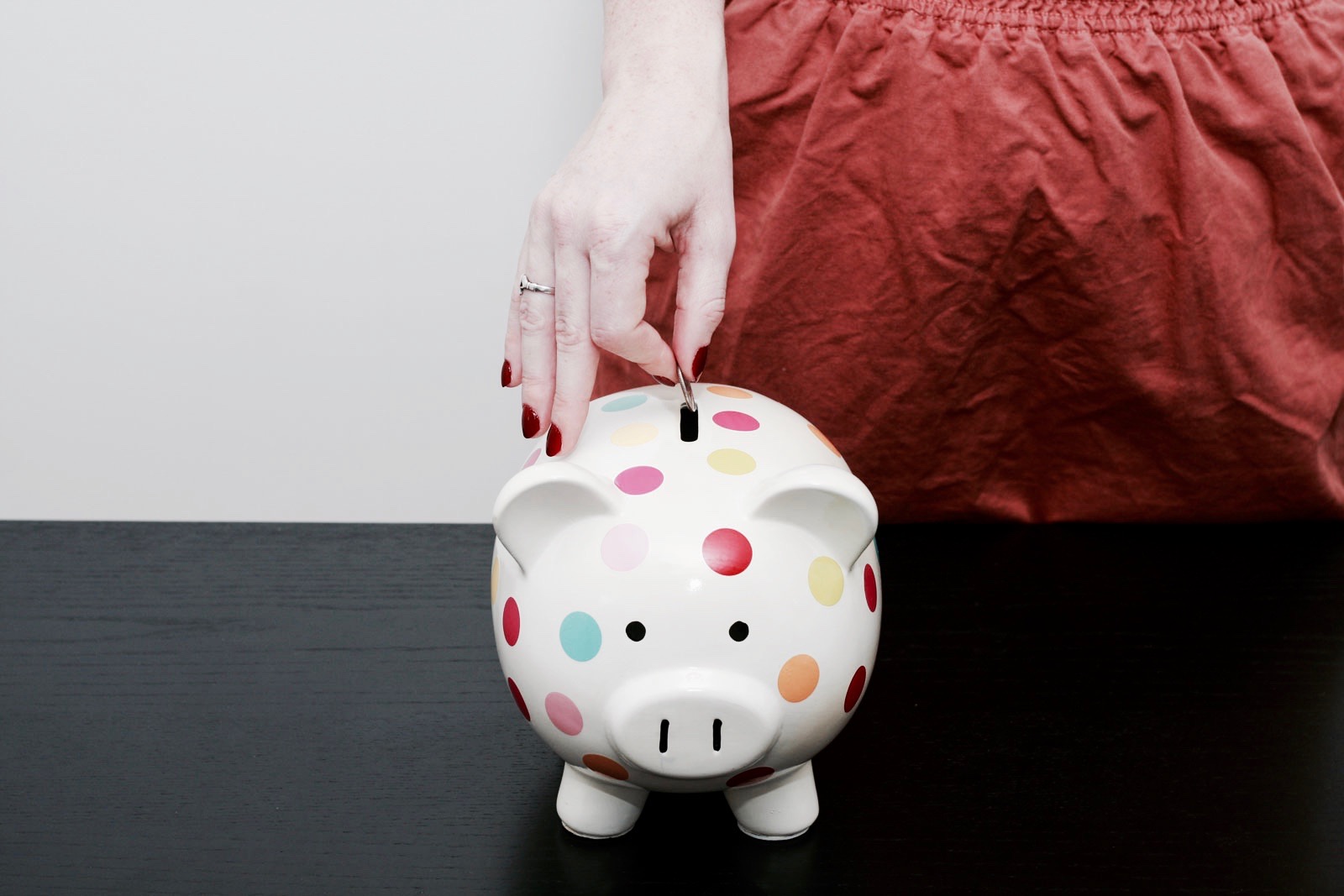 Alyssa deposits a coin in a polka dot piggy bank