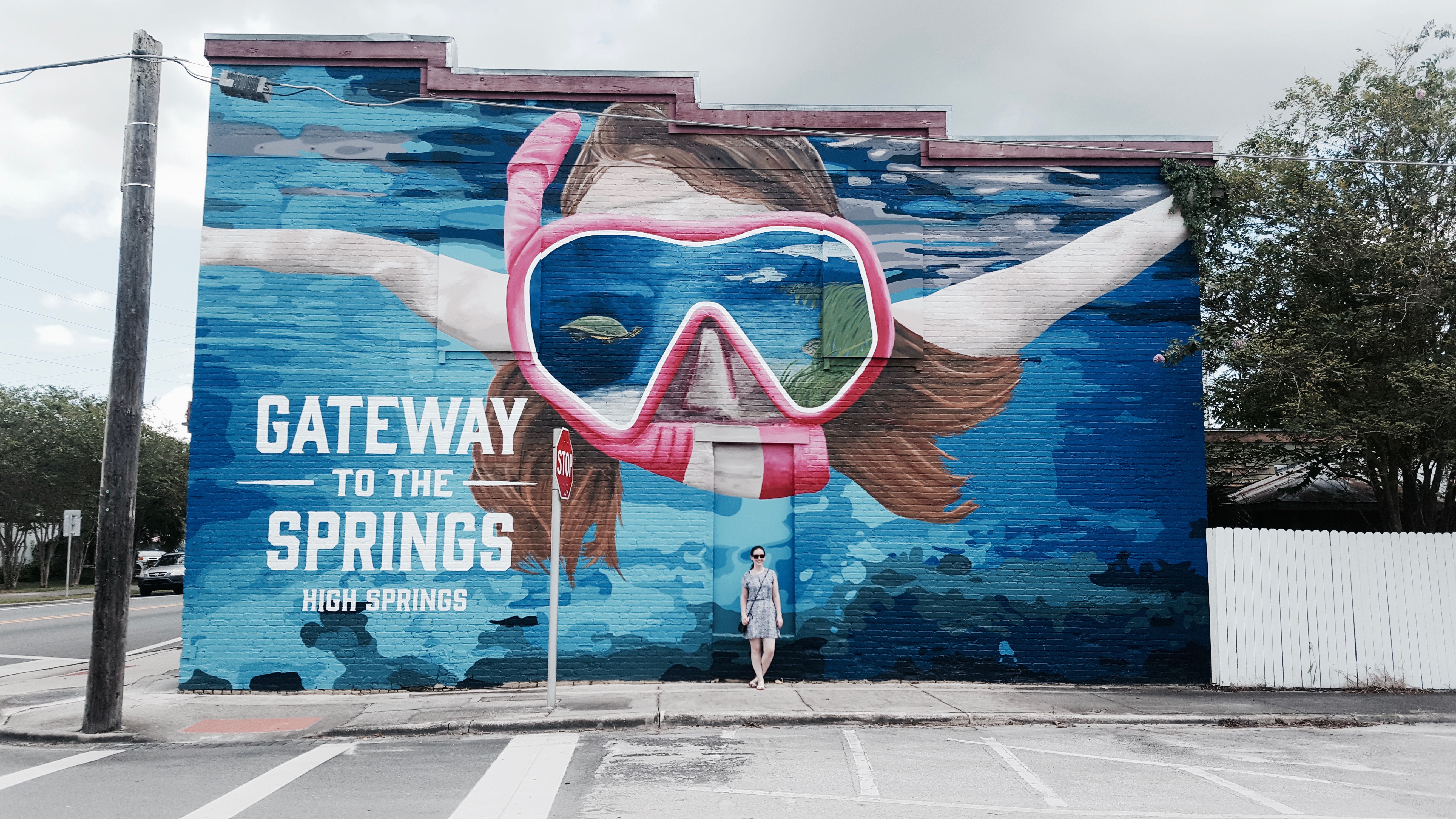 Alyssa with a mural that reads "Gateway to the Springs"