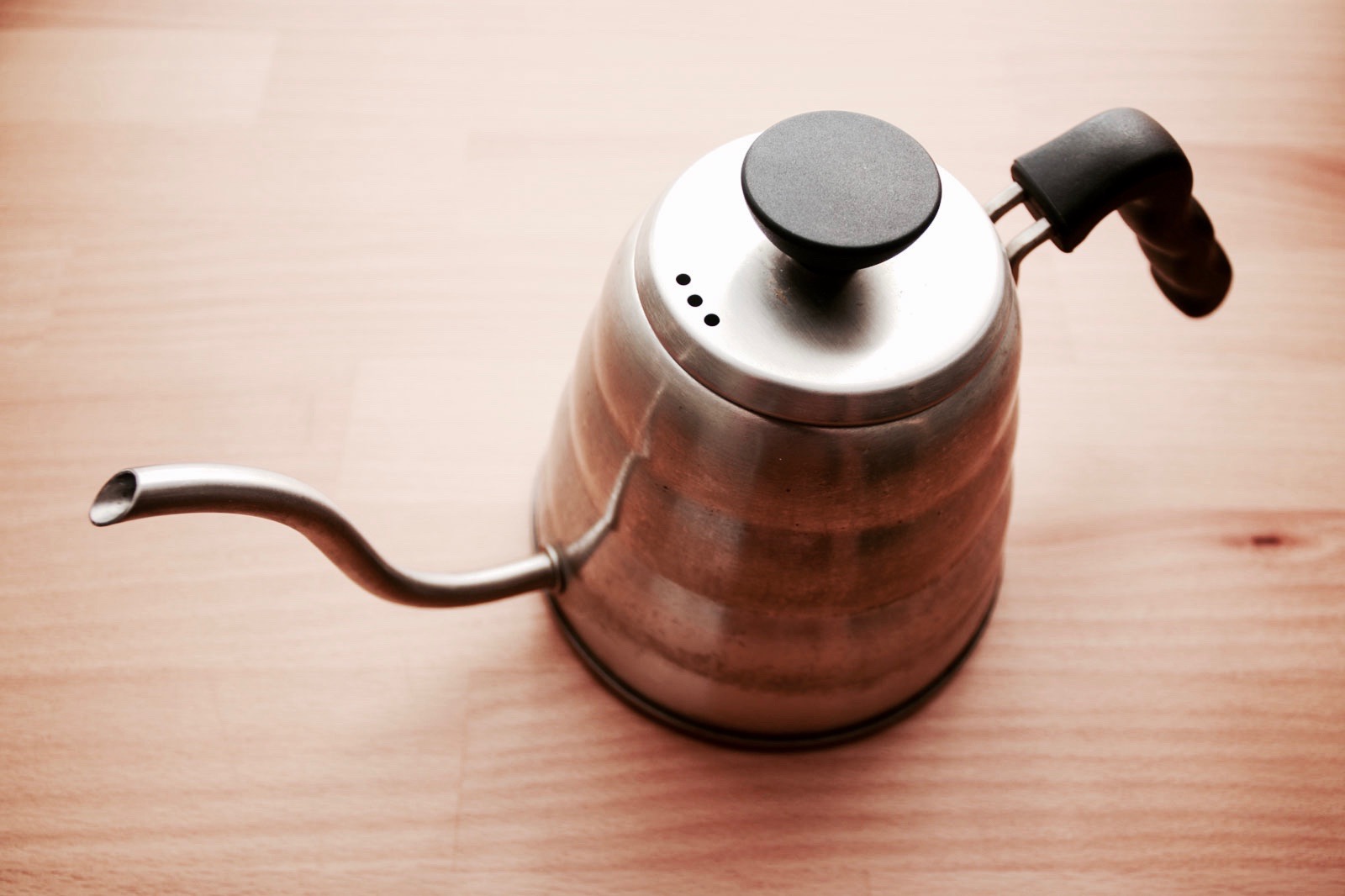 A gooseneck coffee kettle on a wooden countertop