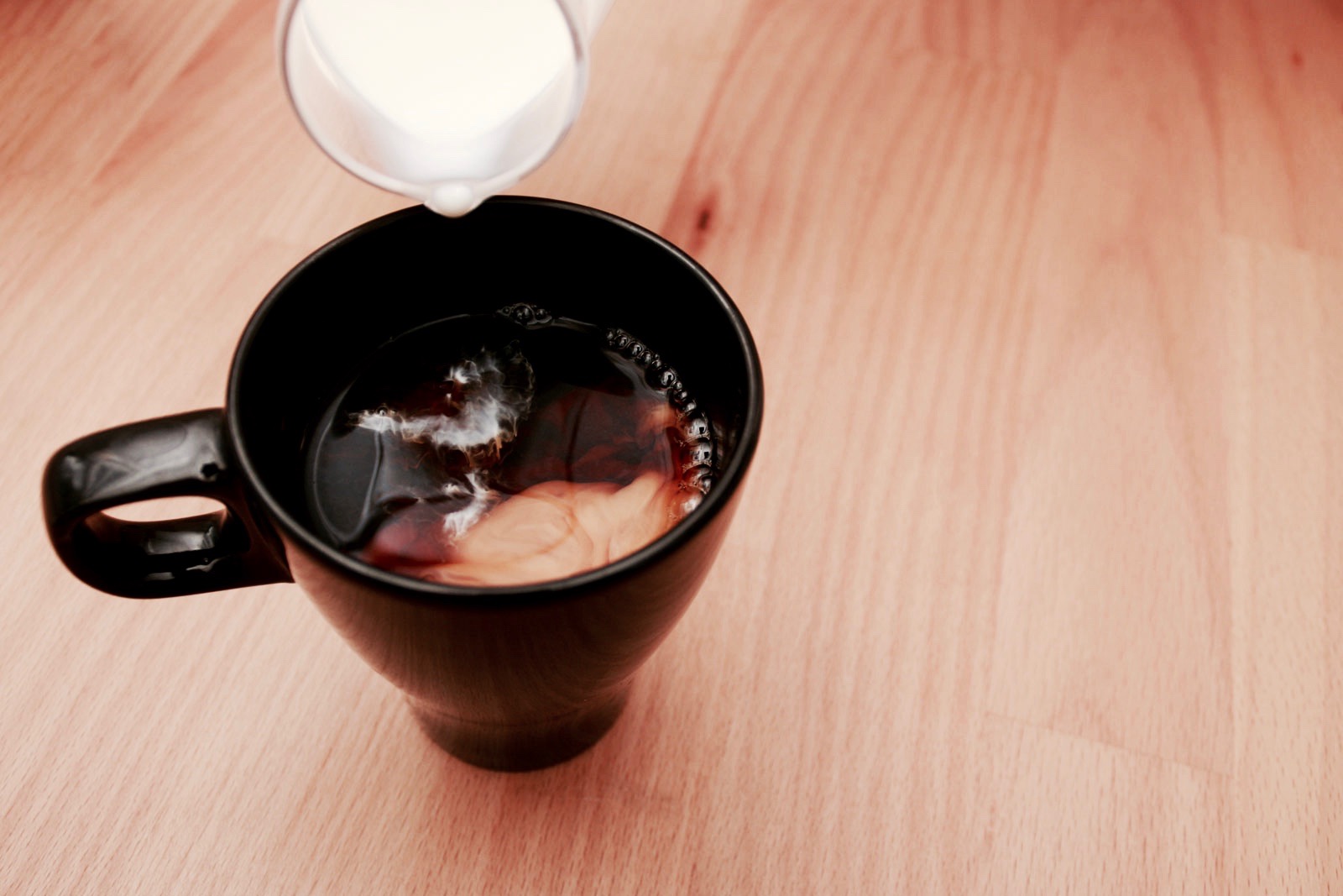 Pouring creamer into coffee