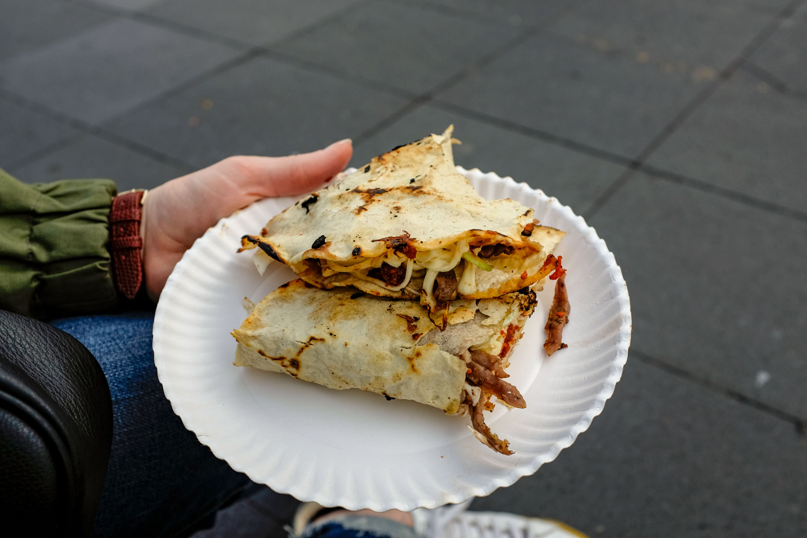 Alyssa holds a plate with a large quesadilla at a festival