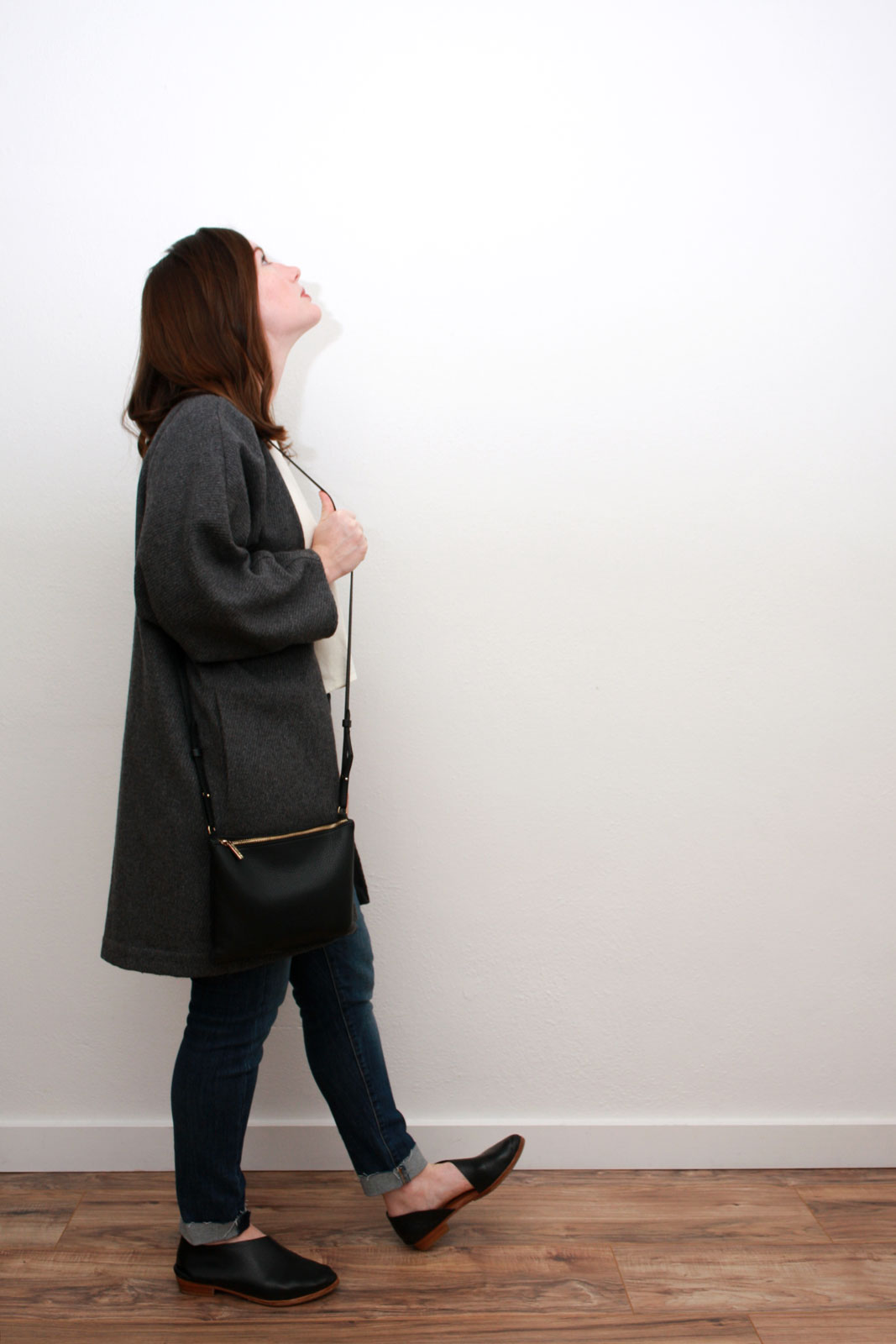Alyssa wears a cream silk top, blue skinny jeans, grey cardigan and black asymmetrical flats while looking upward