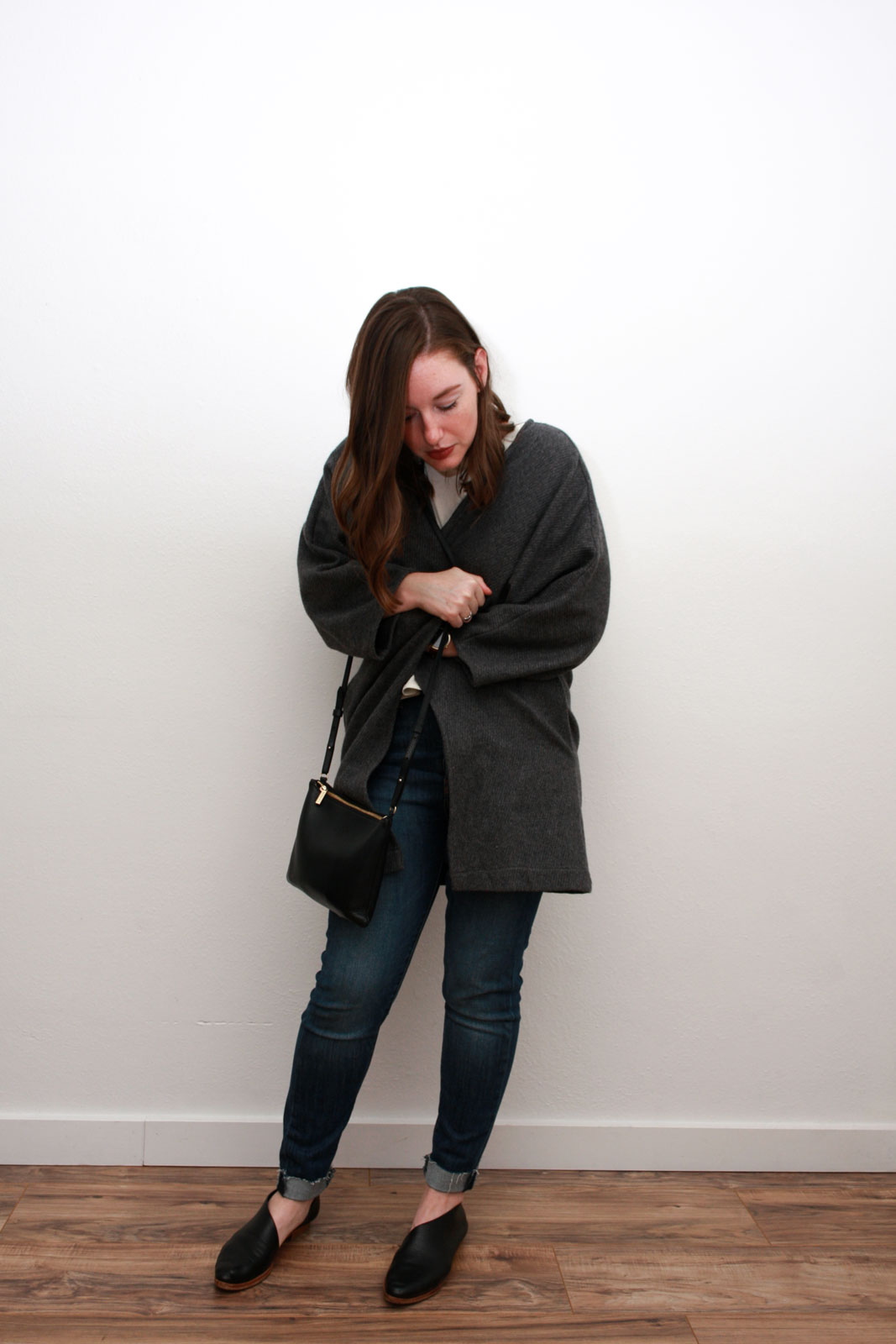 Alyssa wears a cream silk top, blue skinny jeans, grey cardigan and black asymmetrical flats while feeling cozy