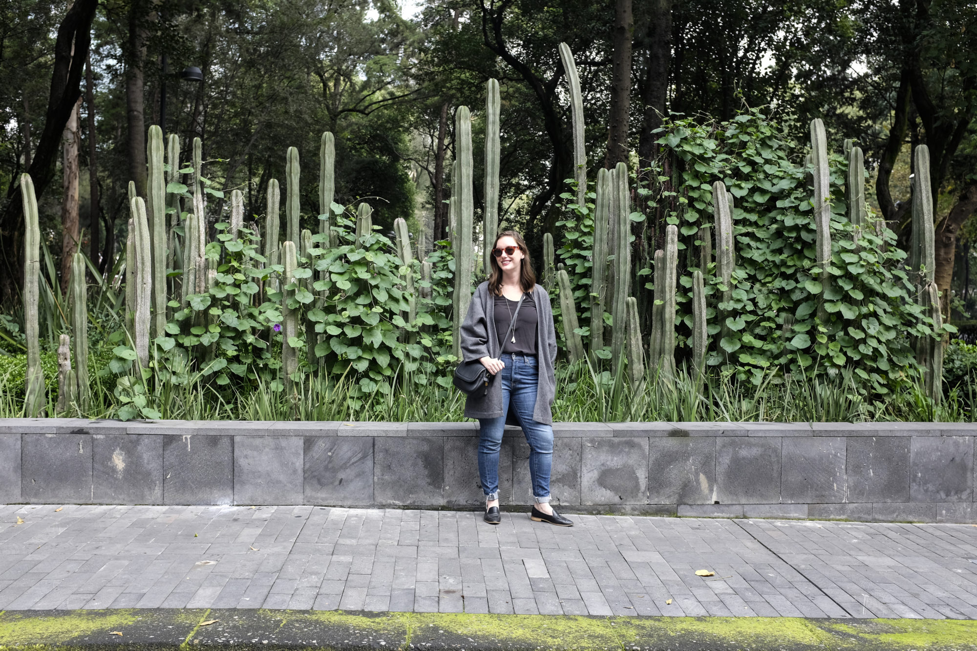 Alyssa wears a black tank, grey cardigan, blue jeans, and black loafers in Mexico City