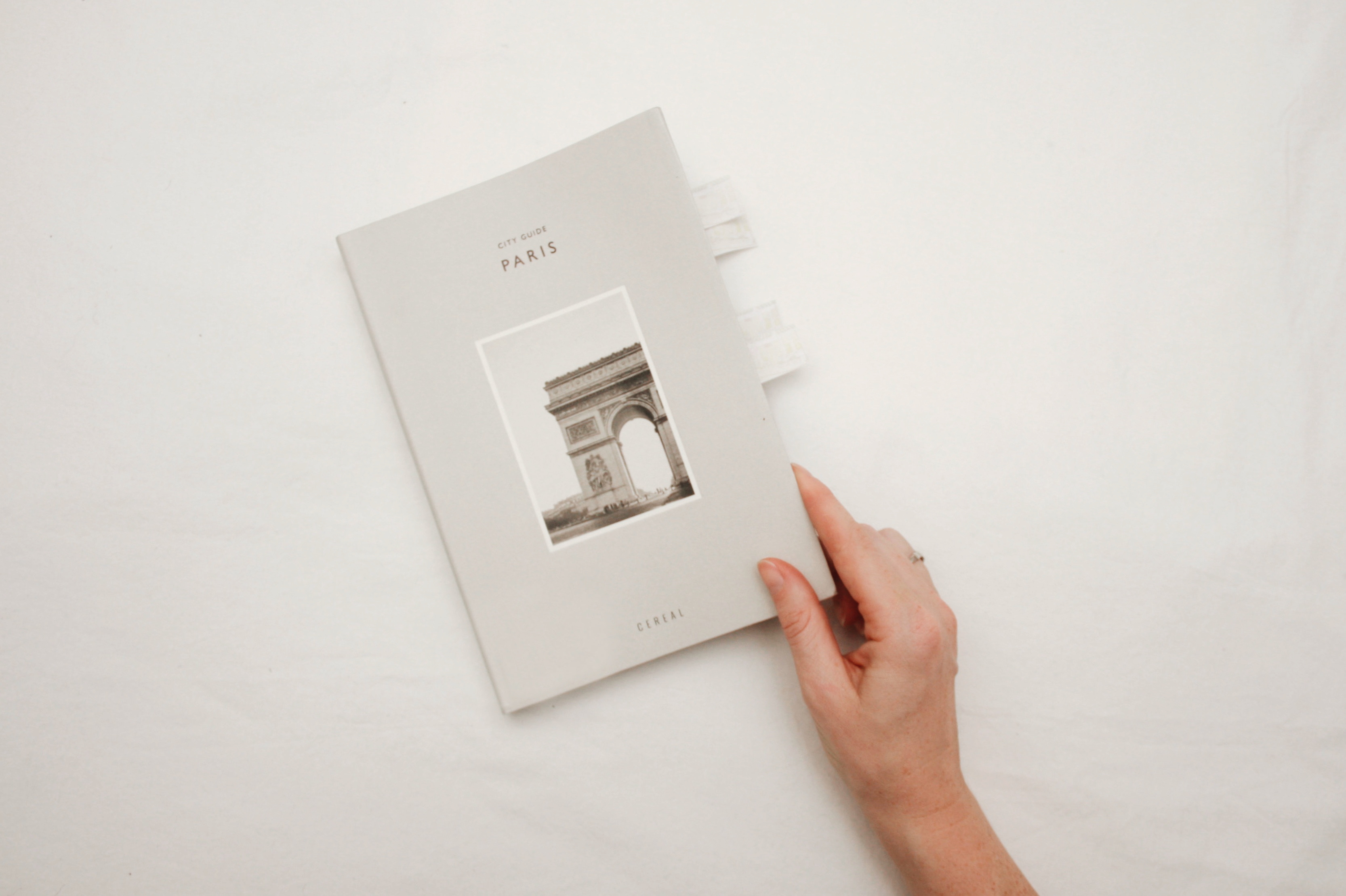 A hand holds a Paris Guide Book