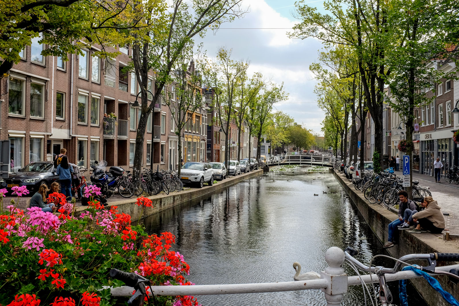 People sit beside a canal in Delft