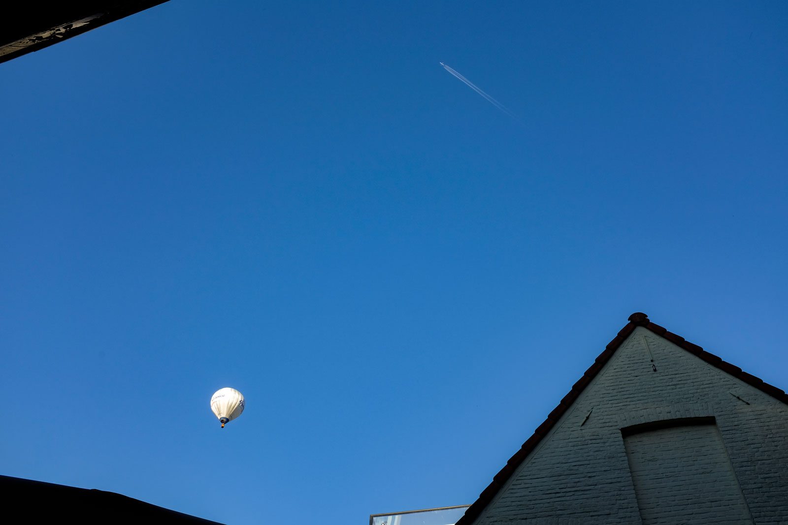 A hot air balloon floats over Bruges