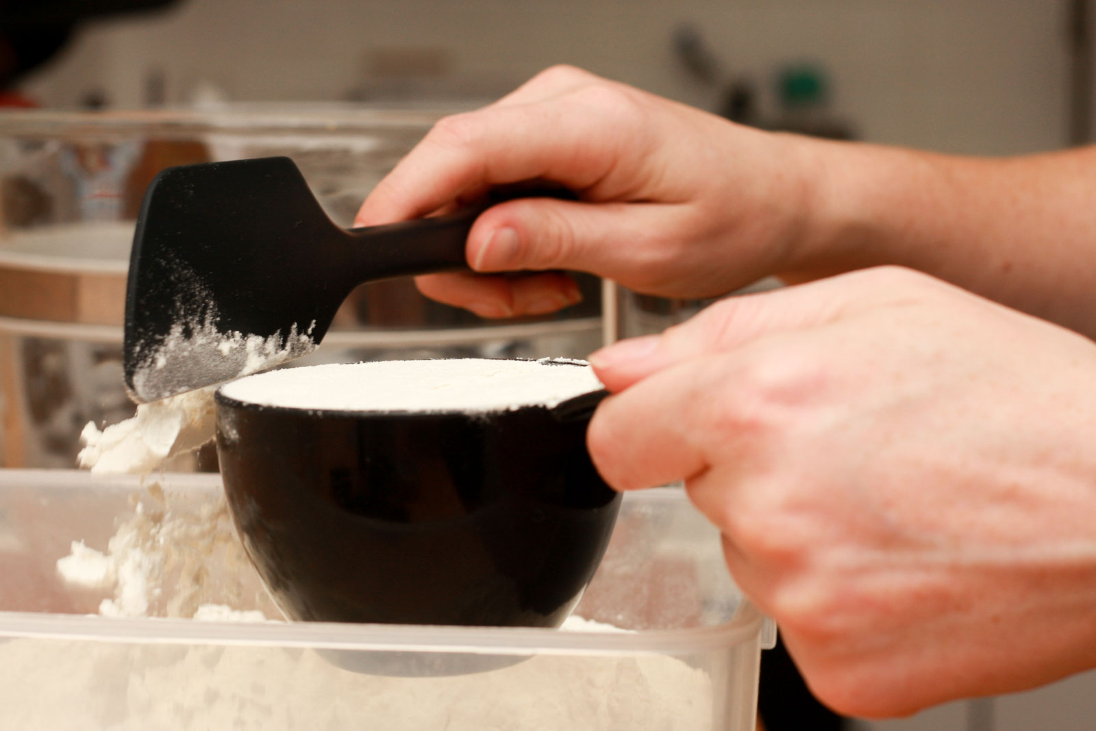 Alyssa levels off a measuring cup of flour