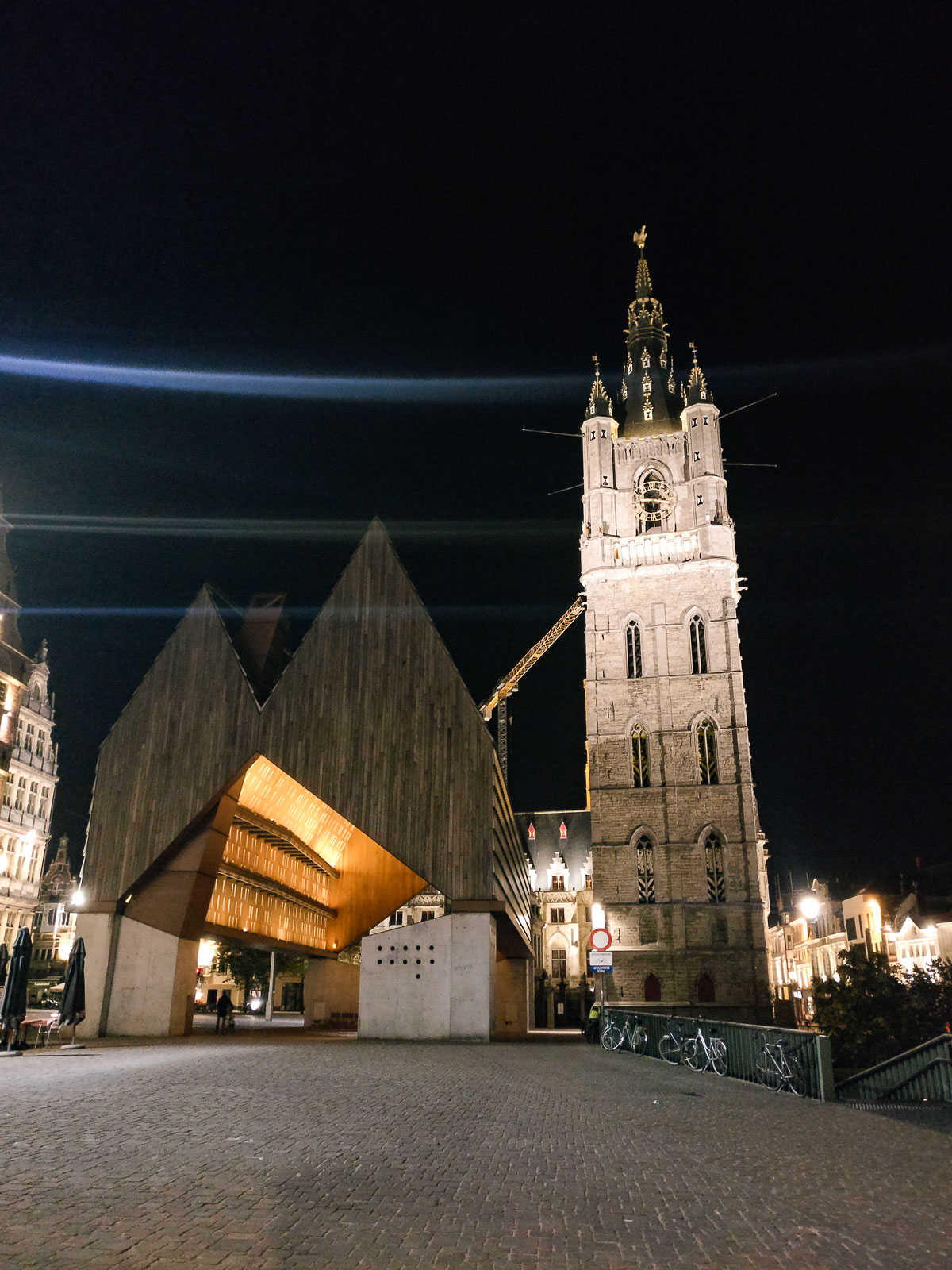 A photo of both the Ghent Stadshal & Belfry at night