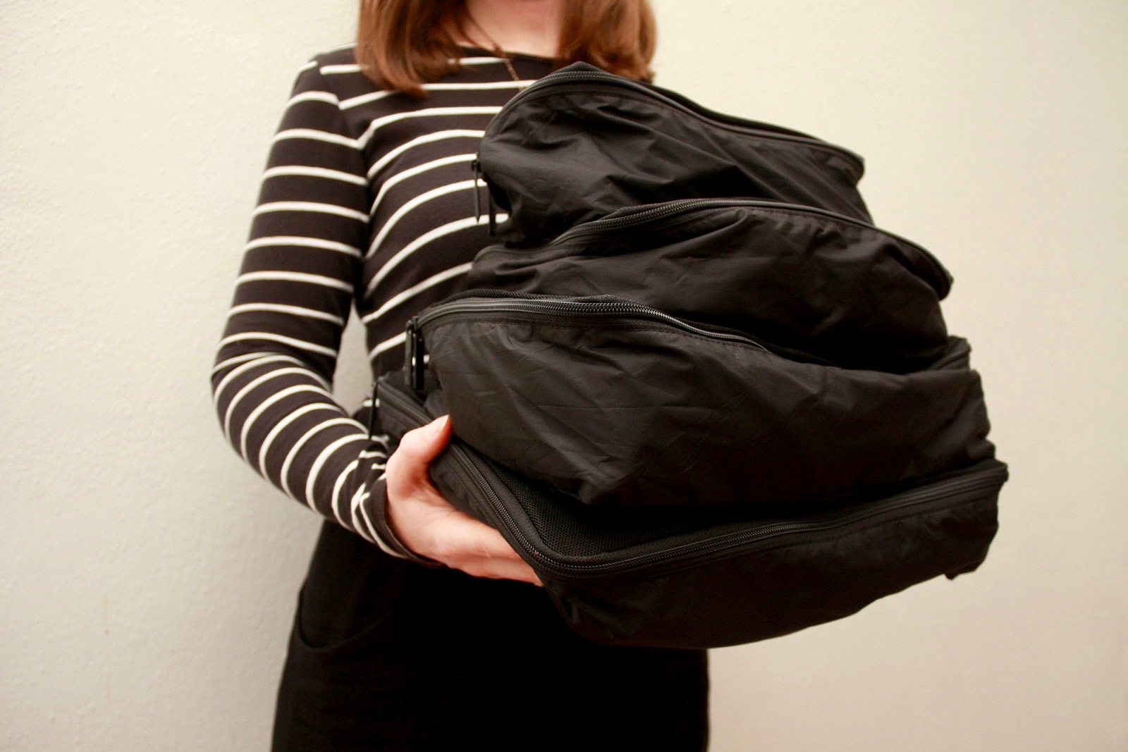 Alyssa holds four packing cubes from Away