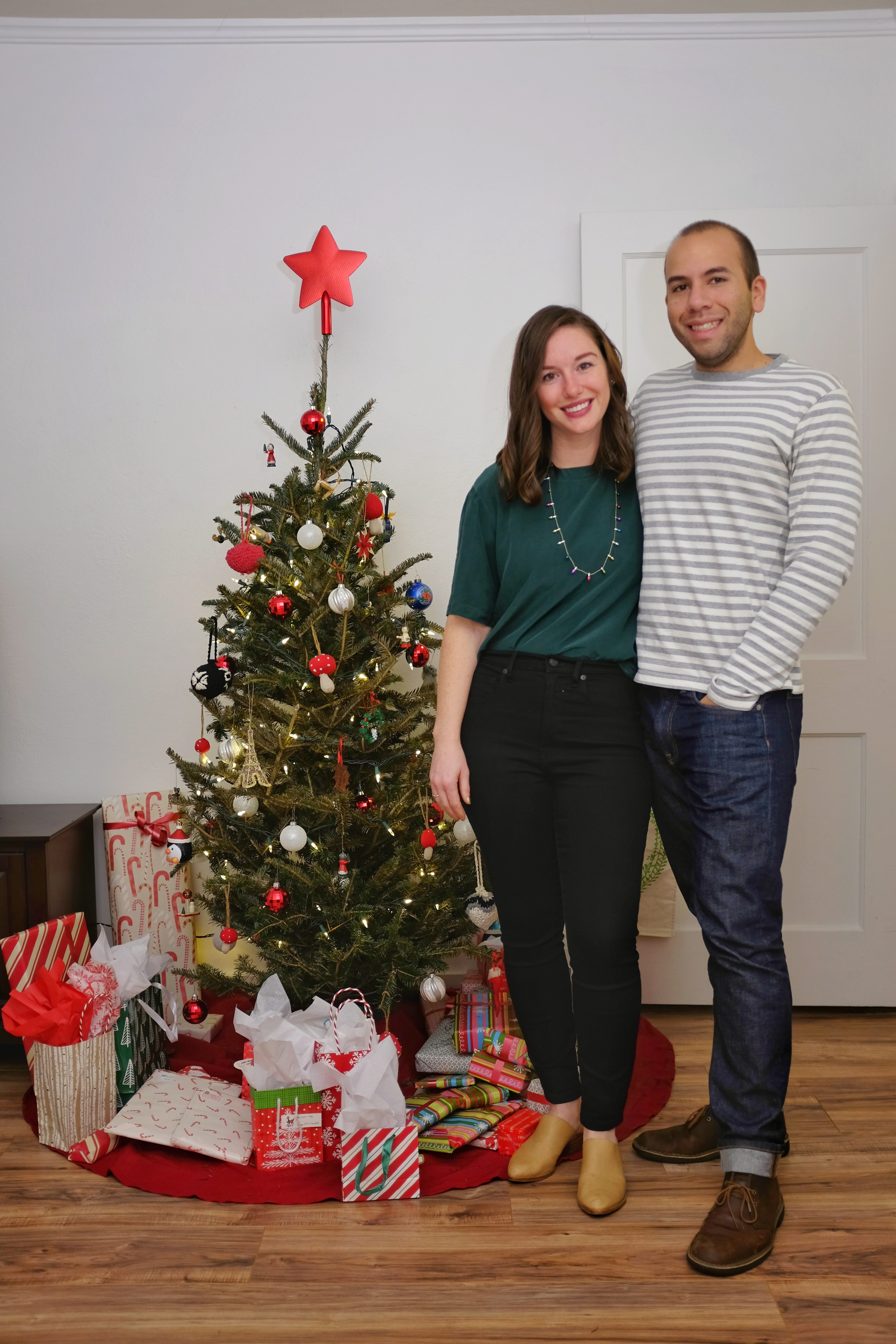 Alyssa and Michael take a photo in front of the Christmas tree