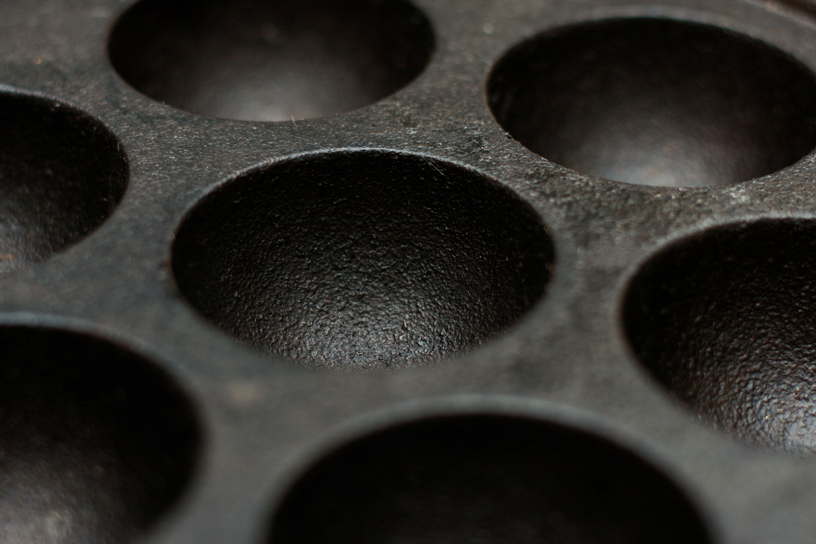 picture of an aebleskiver pan - a cast iron pan with half-circle cutouts