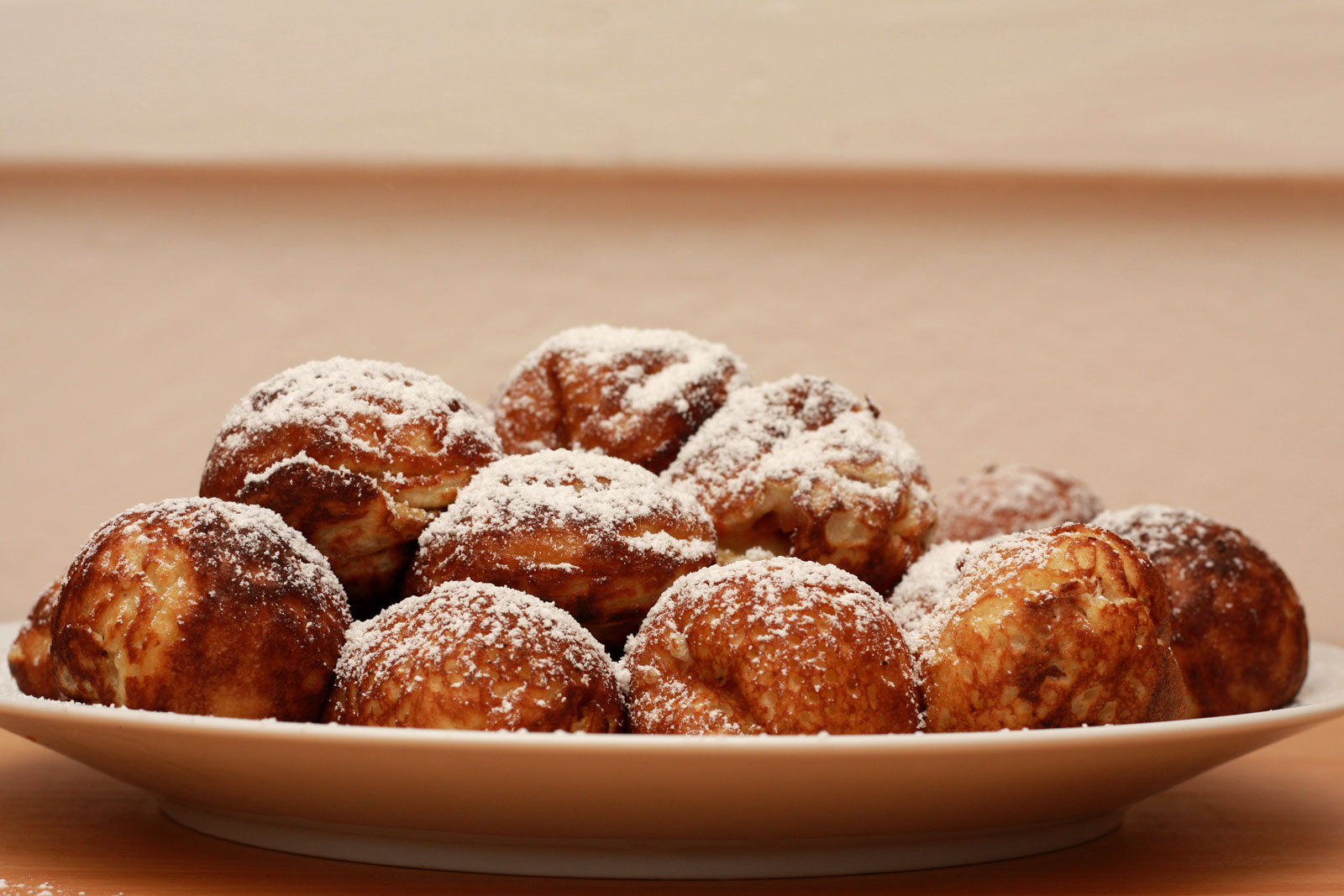 A plate of aebleskiver with powdered sugar on top