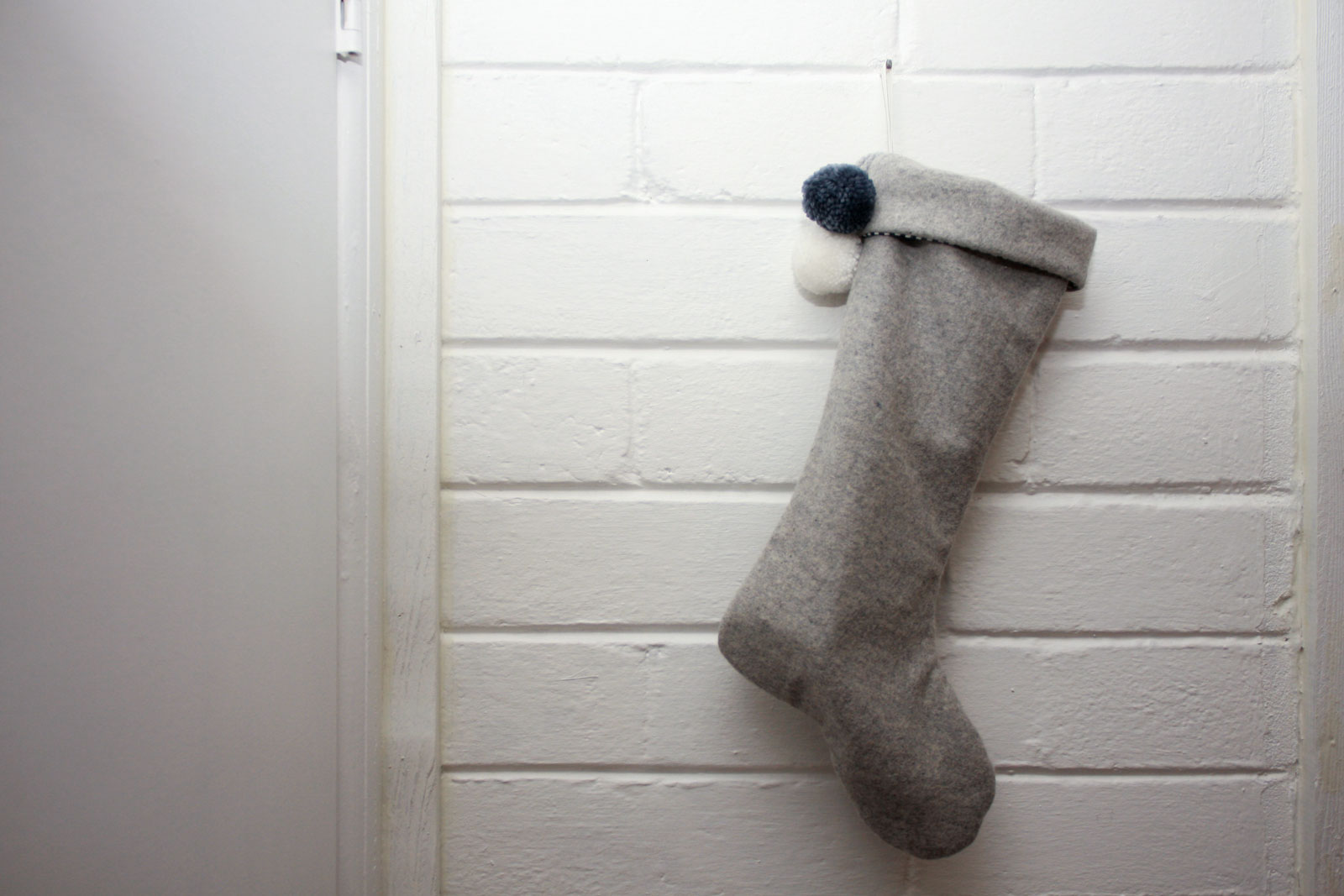 A grey stocking hangs on a white brick wall