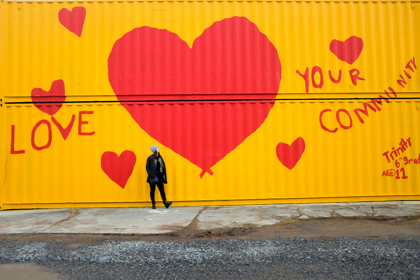 Alyssa stands in front of the Asheville Love Your Community Mural