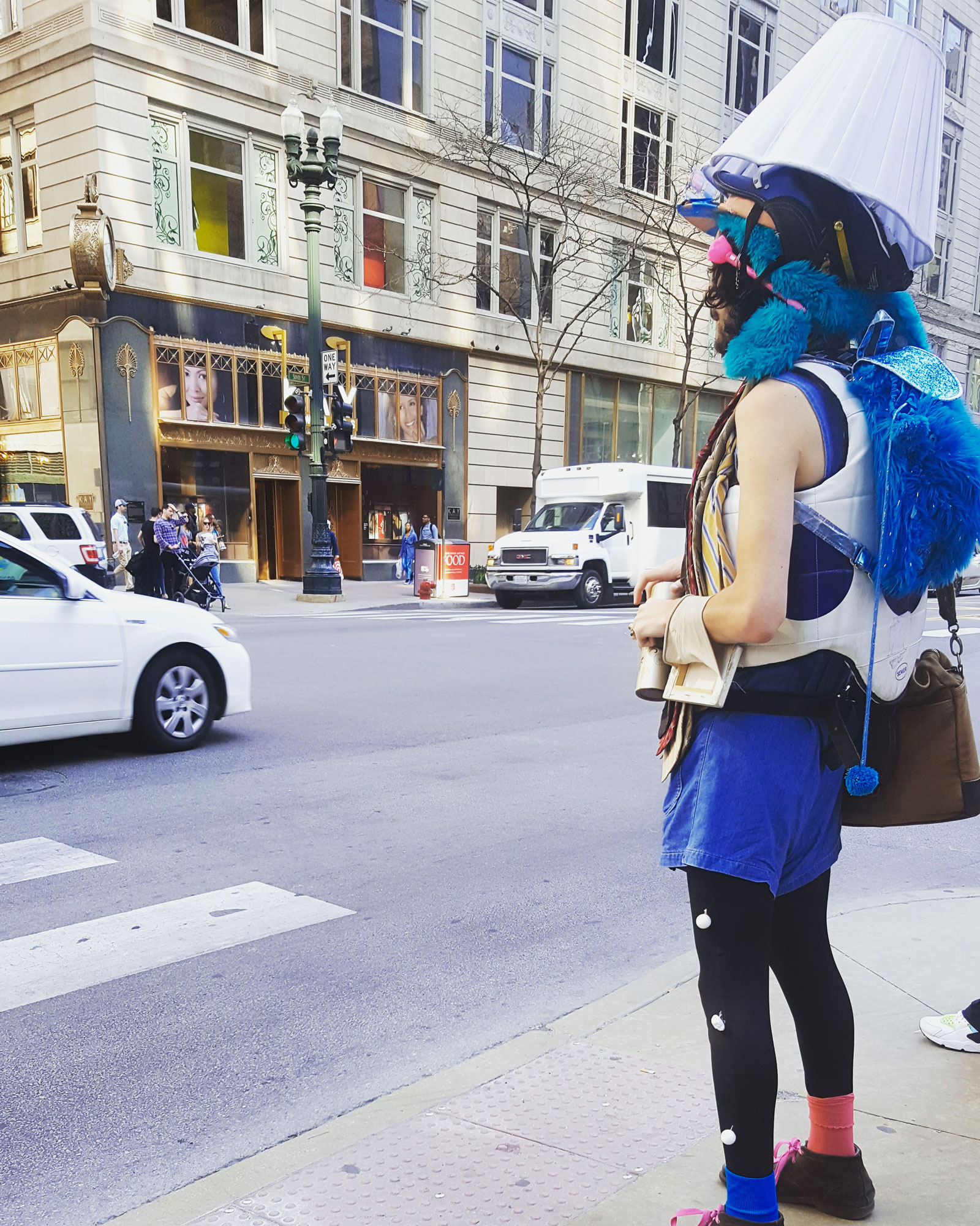 A person wearing eccentric clothing and lampshade hat on a Chicago street corner