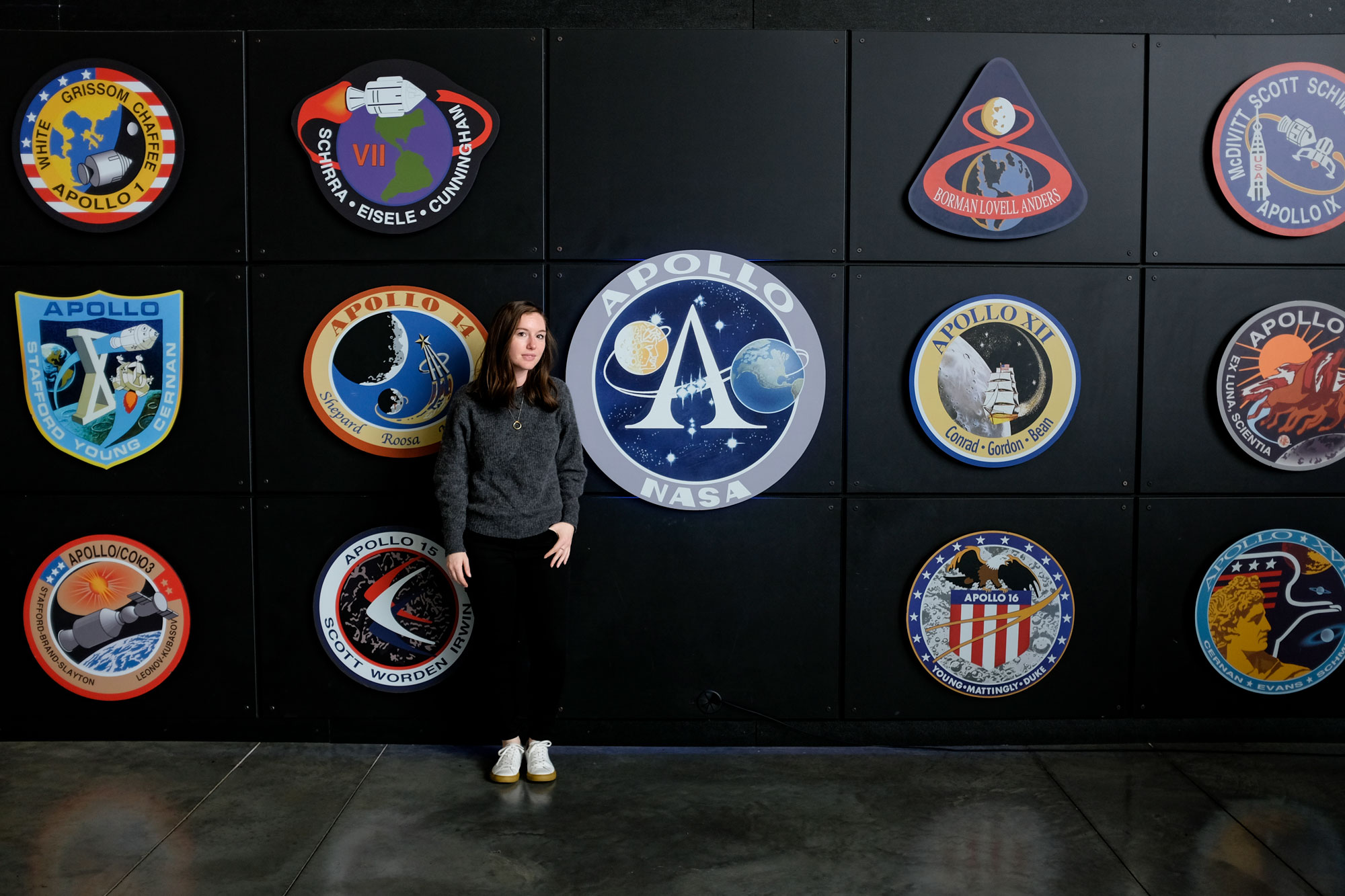 Alyssa stands in front of a wall full of NASA logos