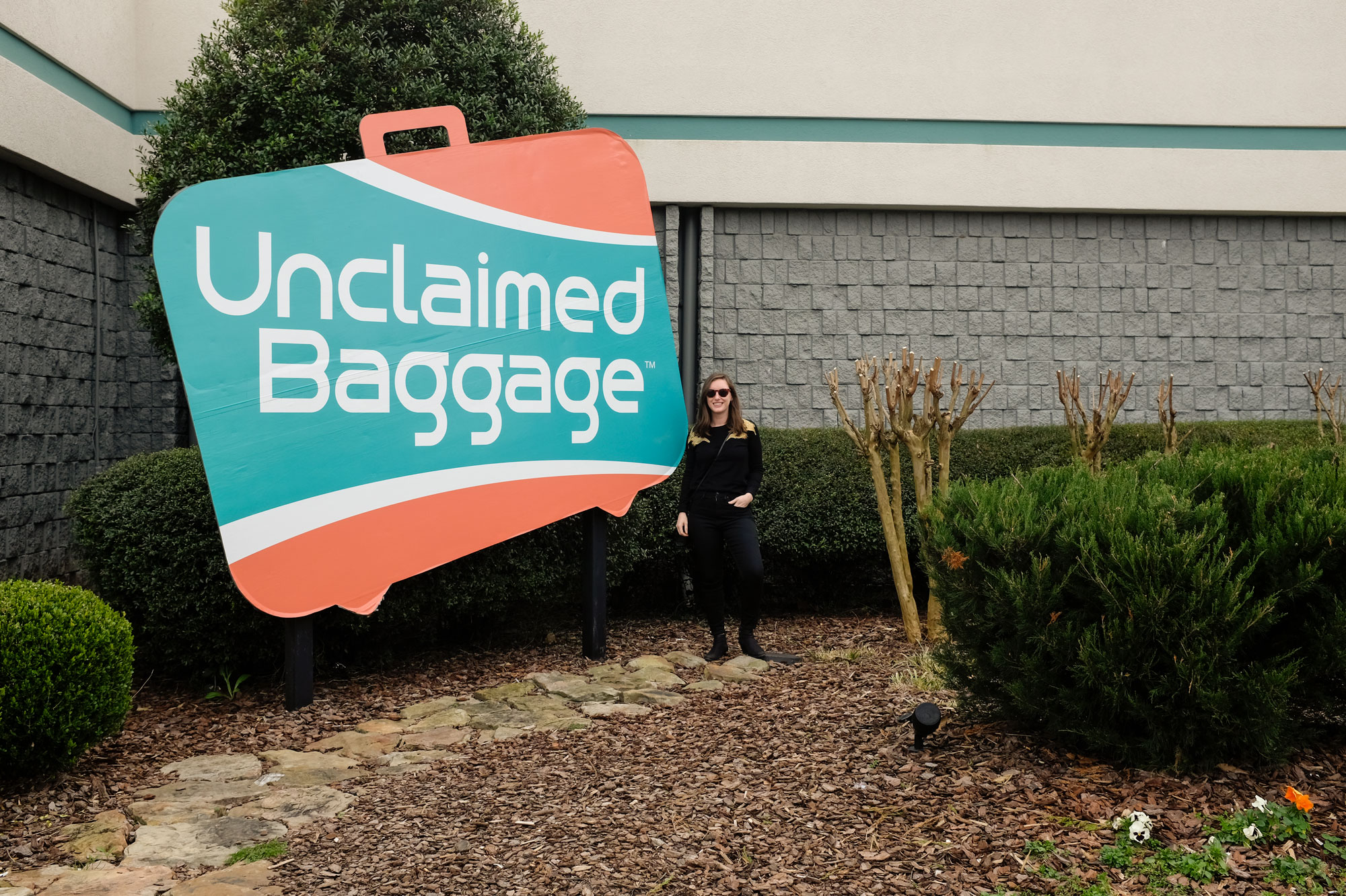 Krystal standing in front of sign at Unclaimed Baggage Entrance