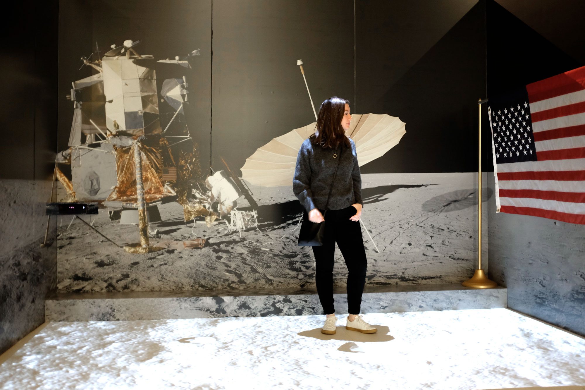 Alyssa standing on a lunar landscape in a grey sweater and black denim