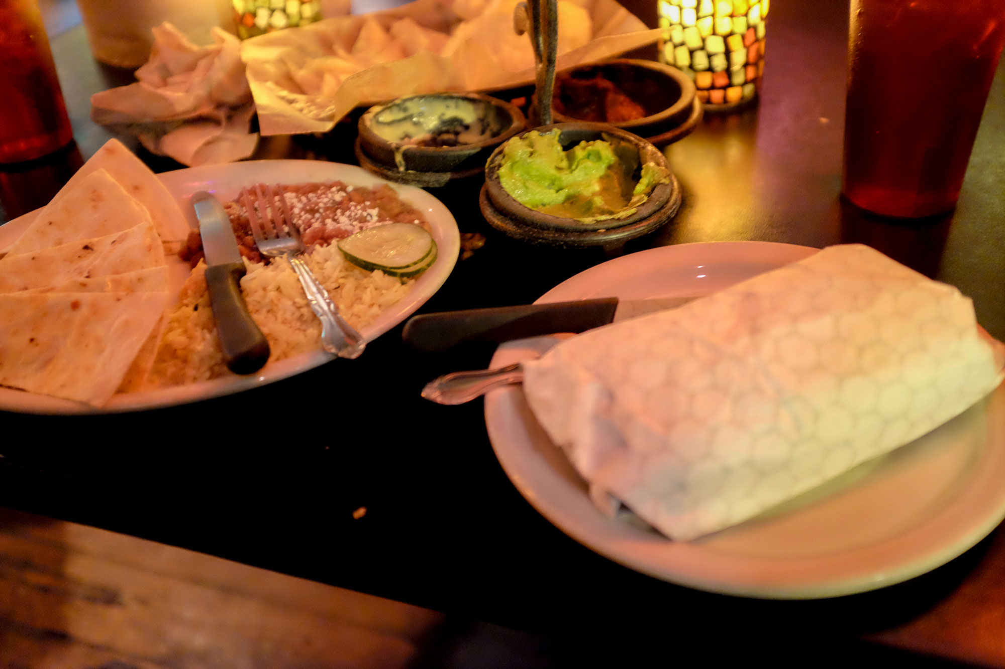 table with dishes from El Rey burrito lounge with a very large burrito