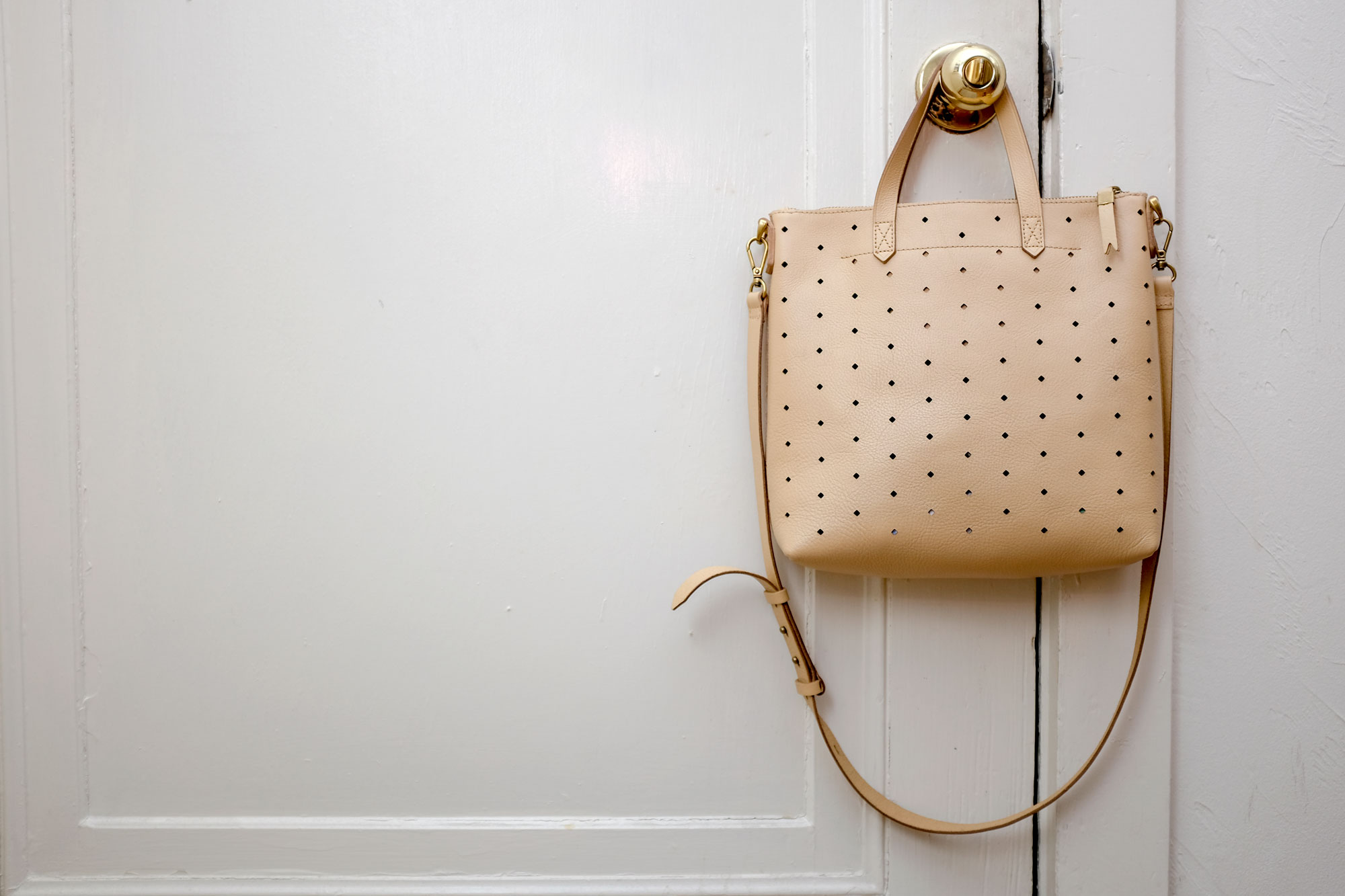 Alyssa's neutral tote bag hanging from a door knob.