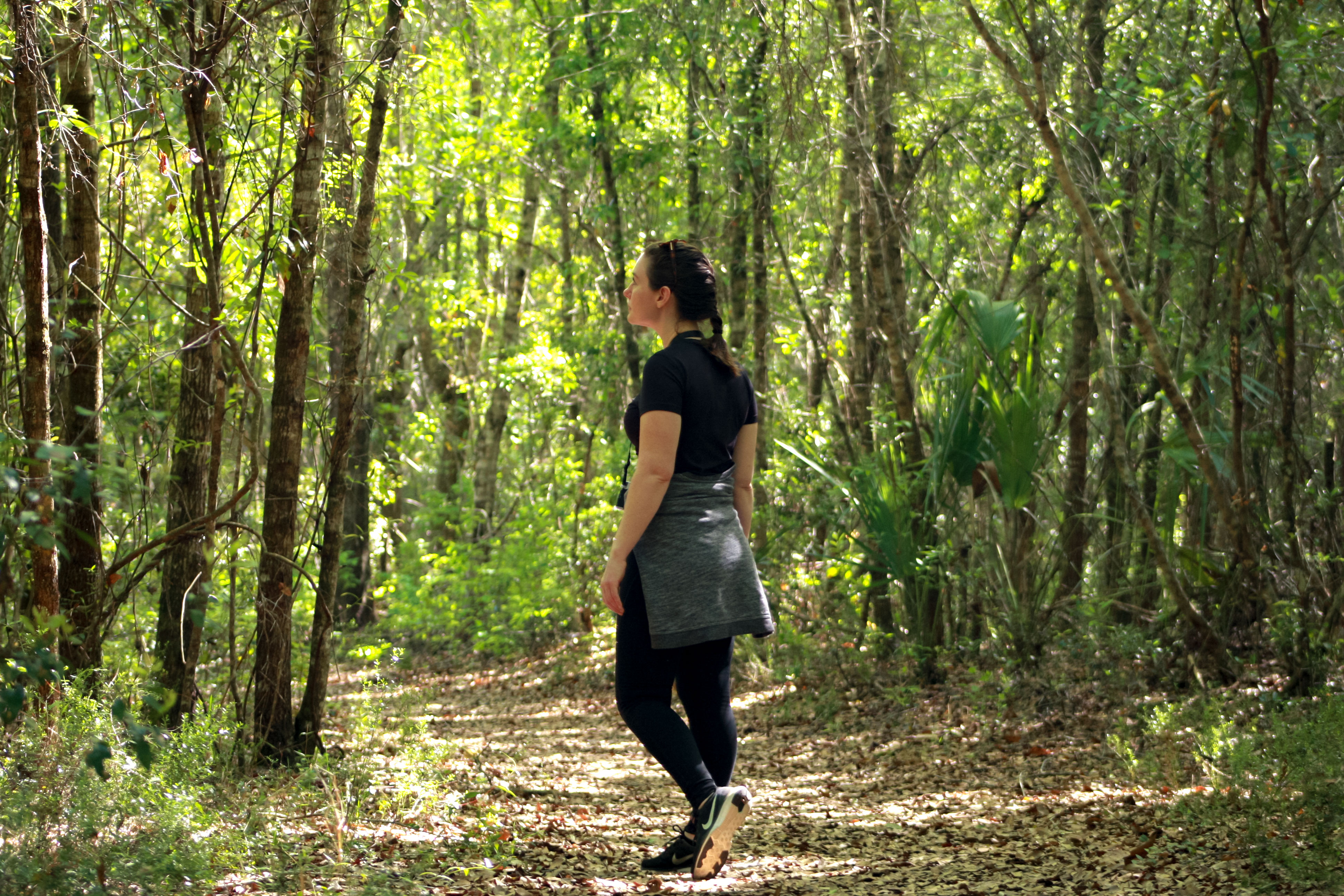 Alyssa walking a path in the woods in exercise clothing